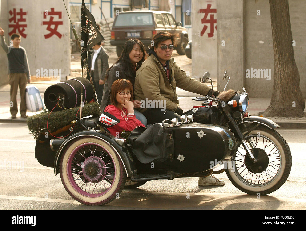 Un uomo cinese e due donne siedono nel loro moto e side-car in attesa di una luce verde nel centro cittadino di Pechino su Venerdì, 21 aprile 2006. Come la Cina continua ad aprire le sue porte al Western beni, servizi e intrattenimento, la sua gioventù e classe media emergente aveva scelto di abbracciare le tendenze internazionali invece dei tradizionali dogane cinesi e ideologia. (UPI foto/Stephen rasoio) Foto Stock