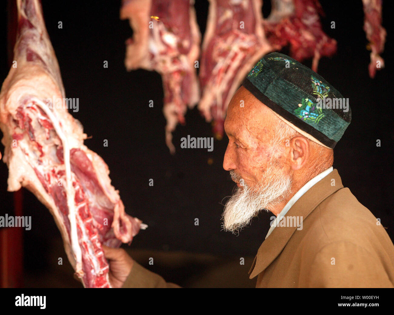 Un anziano uomo Uighur ispeziona fresco agnello macellato per la vendita su un mercato Uighur nel centro di Urumqi, Xinjiang, 14 settembre 2006. Tra le vittime della "guerra al terrorismo" sono ampiamente dimenticate popoli musulmani del Xinjiang. Questa immensa area è quasi grande come tutta l'Europa occidentale ed era tradizionalmente abitati da Musulmani uiguri, Kazaks, e alcuni piccoli gruppi. Tuttavia, gli ultimi due decenni hanno visto un afflusso massiccio di Han immigrati cinesi e la nativa popolazione musulmana è in pericolo di essere sopraffatti nel proprio cuore. Il risentimento contro cinese Han e politico Foto Stock