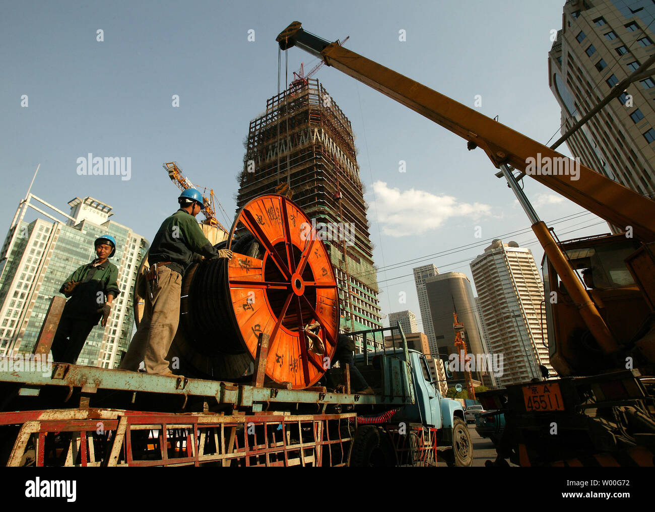 Lavoratori edili cavi di carico su un camion vicino al China World Tower tre in costruzione nel distretto centrale degli affari di Pechino il 25 aprile 2007. La torre sarà il più alto a Pechino una volta completato. Della Cina di banca centrale si aspetta che l'economia di rallentare un po' nel 2007, ma per mantenere la crescita a doppia cifra per il quinto anno in una riga, secondo una relazione della sua divisione di ricerca pubblicato il mese scorso. (UPI foto/Stephen rasoio) Foto Stock