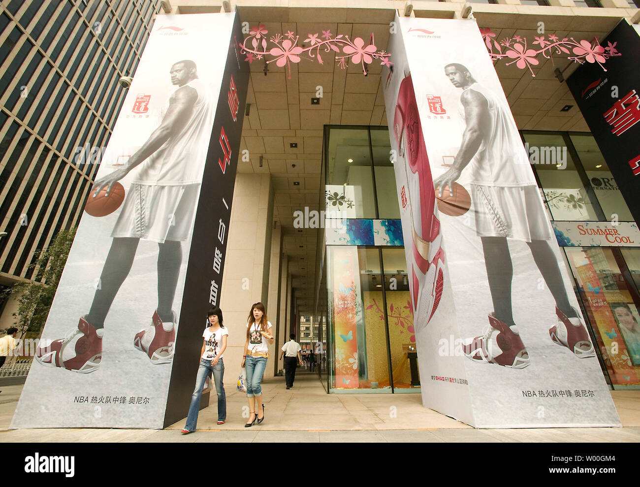 Due donne di lasciare un nuovo internazionale fashion mall, prominente la visualizzazione di pubblicità massiccia per il cinese-realizzato Shaquille O'Neal scarpe, nel centro cittadino di Pechino in Cina il 28 agosto 2007. La Cina ha lanciato una campagna la scorsa settimana per migliorare la qualità dei suoi prodotti di consumo in un tentativo di ristabilire la fiducia nelle sue industrie che hanno colpito dai recenti scandali di sicurezza. (UPI foto/Stephen rasoio) Foto Stock