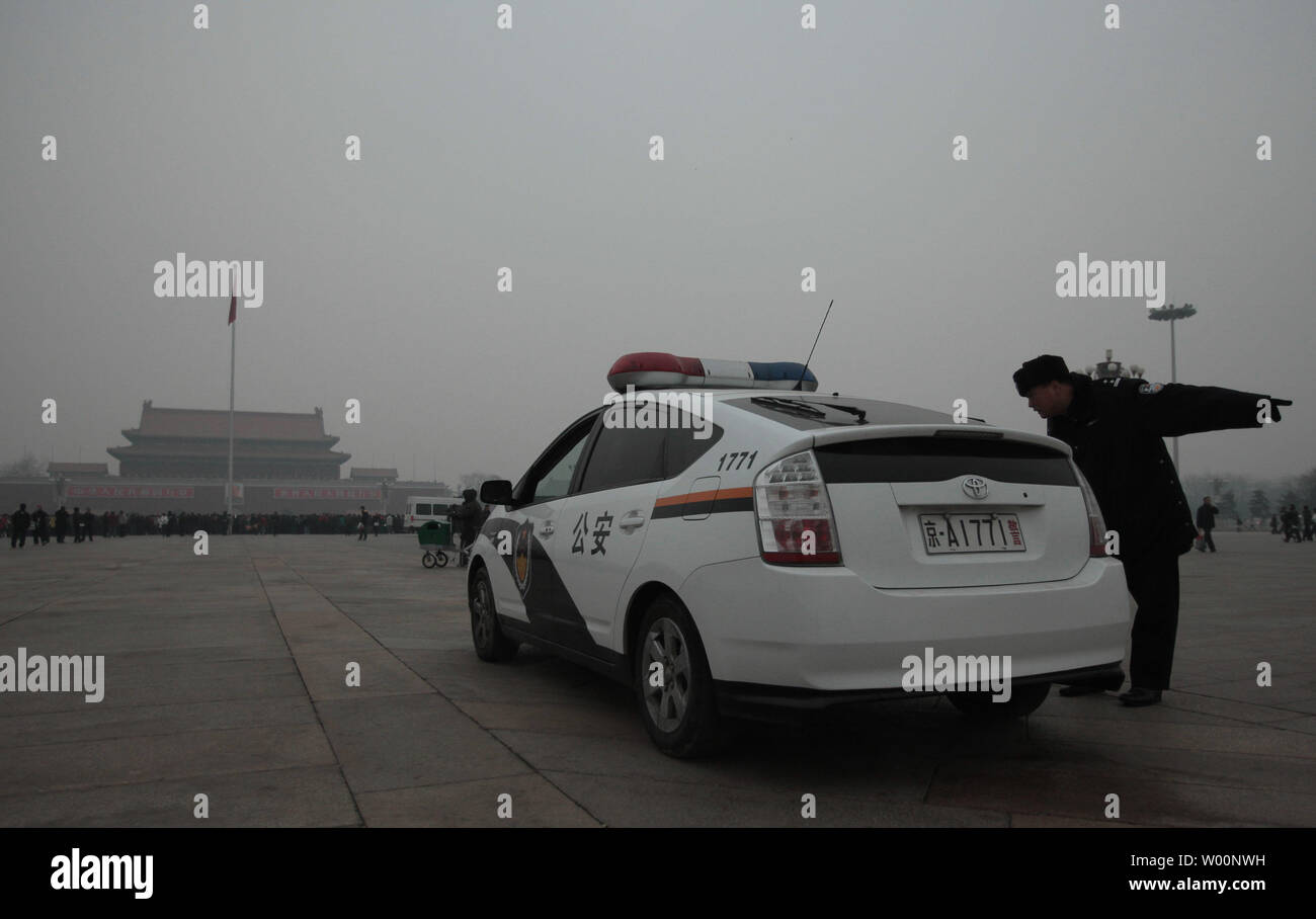 Un Cinese auto della polizia, che è un ibrido di Toyota Prius, monitora la folla in piazza Tiananmen a mezzogiorno come una fitta nebbia copre Pechino il 9 dicembre 2009. La Cina, il più grande del mondo nel complesso emettitore di gas ad effetto serra, dice ogni trattativa ha colpito al cambiamento climatico colloqui di Copenaghen dovrebbe ammontare a poco se nazioni sviluppate non adempiono ai voti per tagliare le emissioni di gas. UPI/Stephen rasoio Foto Stock