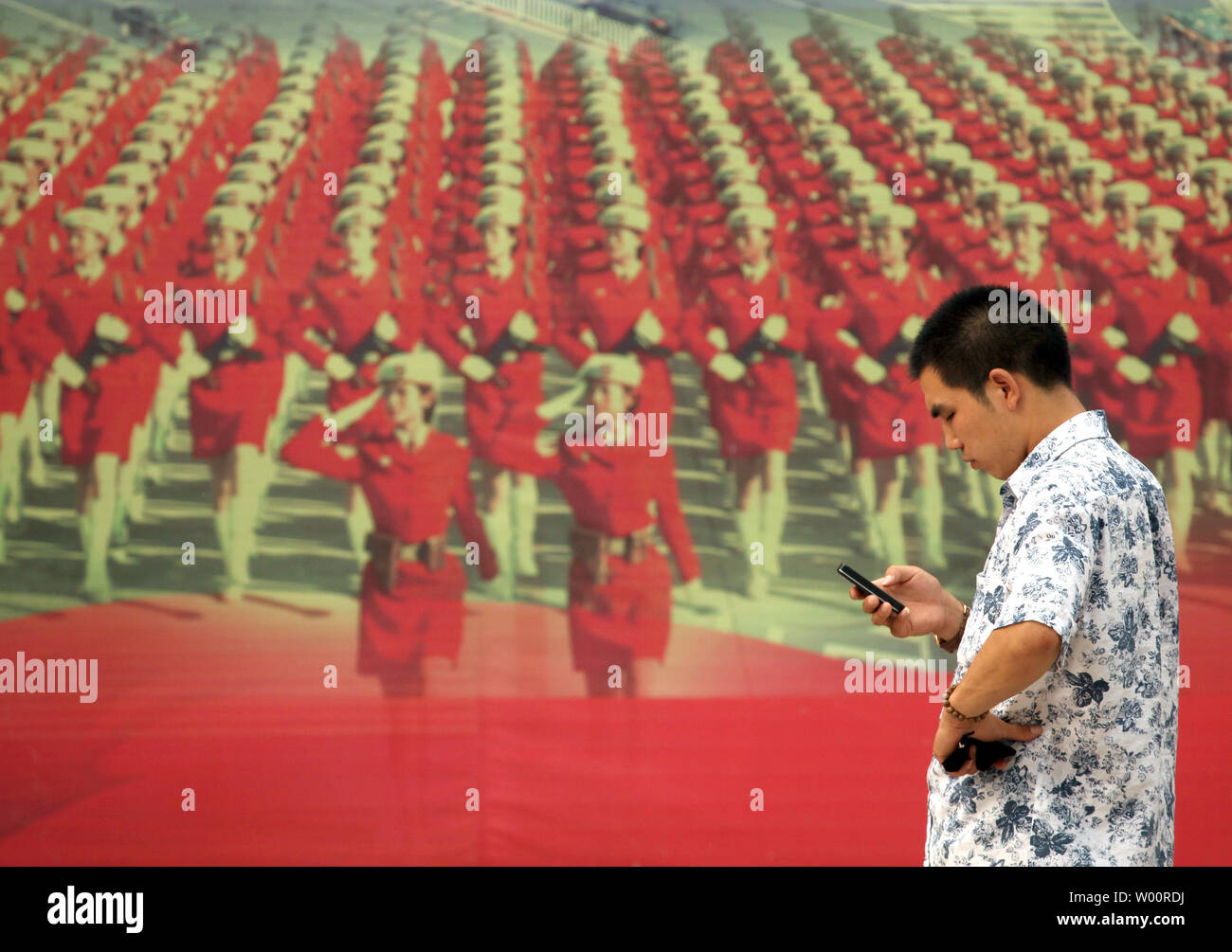 Un uomo cinese fa una telefonata di fronte a un gigante pubblicitario utilizzando immagini patriottica e slogan per promuovere una nuova, international shopping arcade nel centro cittadino di Pechino il 3 agosto 2010. UPI/Stephen rasoio Foto Stock