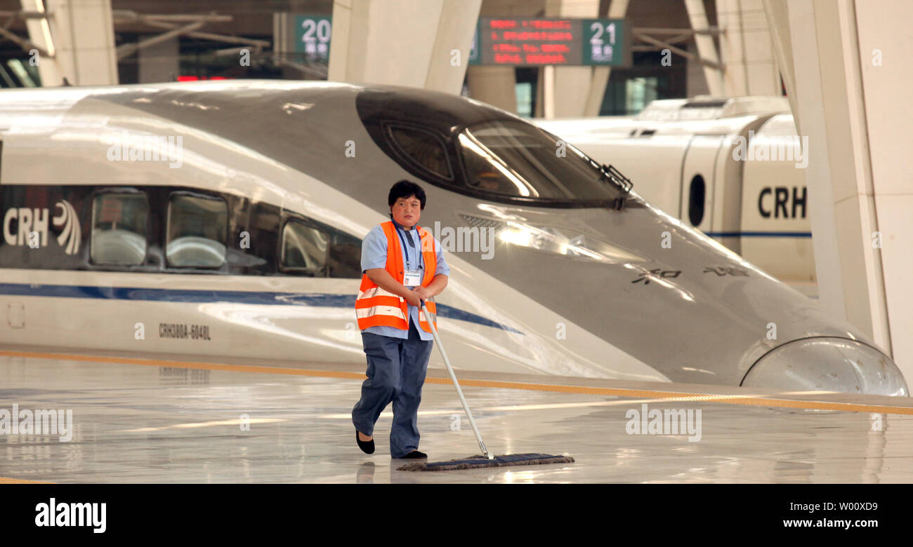 Un lavoratore spazza come CRH i treni ad alta velocità arrivano e partono da Pechino la nuova, modernissima stazione ferroviaria meridionale il 27 giugno 2011. Ingegneri cinesi condotta una prova di esecuzione del Beijing-Shanghai collegamento ferroviario ad alta velocità, giorni prima del suo lancio pubblico. Funzionari, giornalisti e boss della società erano a bordo per i 300km/h (190 mph) treno il viaggio inaugurale. UPI/Stephen rasoio Foto Stock