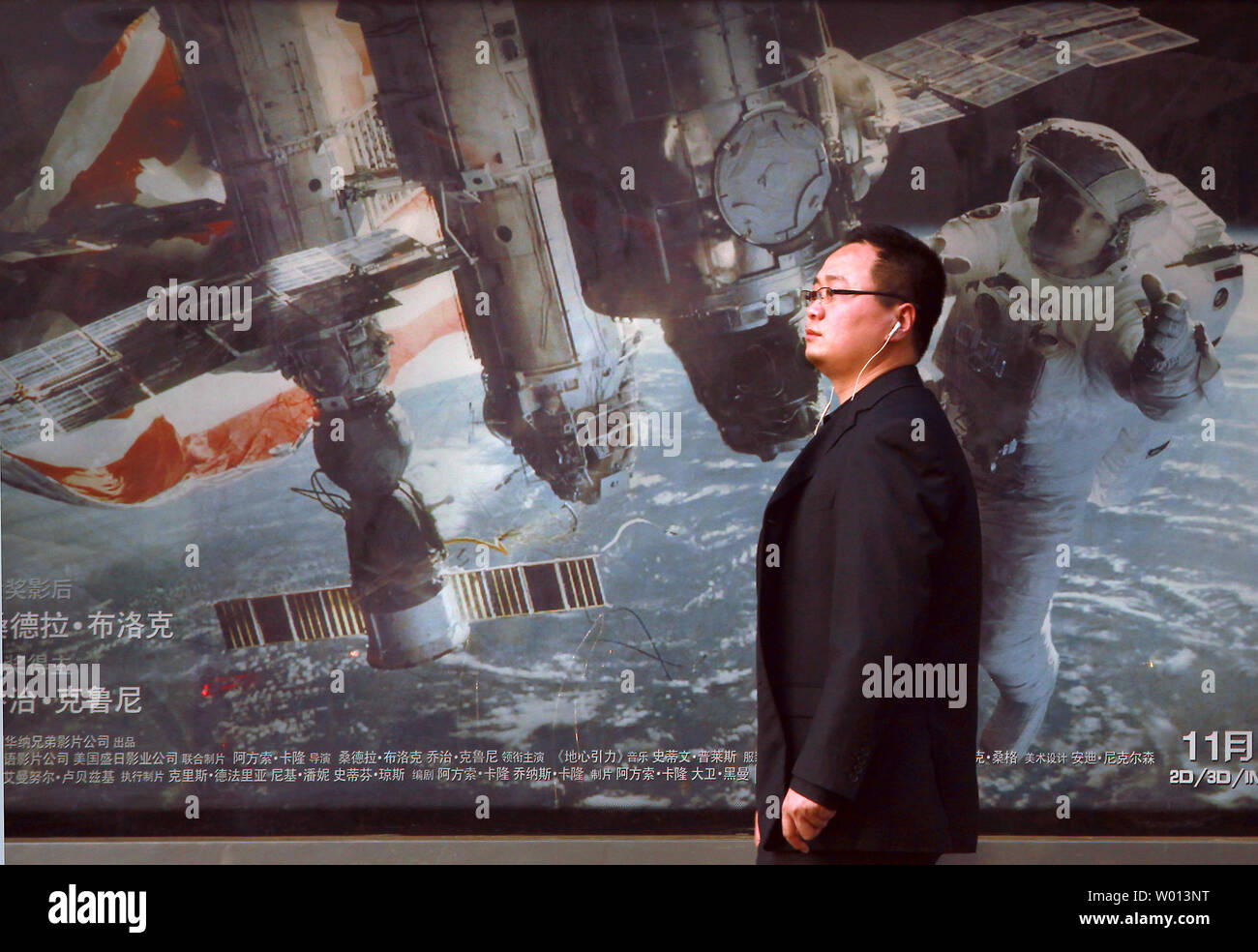 Un uomo cinese attende un autobus di fronte un marciapiede pubblicità per un filmato di circa astronauti americani e la stazione spaziale internazionale a Pechino il 24 novembre 2013. La Cina ha la possibilità nel prossimo decennio per superare gli Stati Uniti nello spazio programmi, costringendo il governo degli Stati Uniti per intensificare il finanziamento della NASA per mantenere la sua posizione di leadership, entrare in partnership con il Cinese o rischiare di cadere dietro la politica spaziale dicono gli esperti. UPI/Stephen rasoio Foto Stock