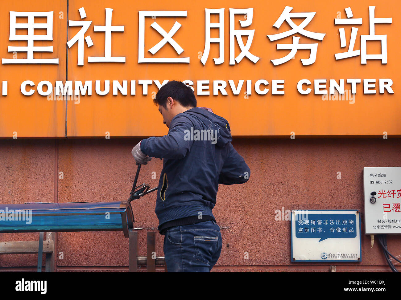 Un Cinese lavoratore edile riparazioni sul tetto di una news stand al di fuori di una zona centro comunitario a Pechino il 21 novembre 2016. Come la maggior parte dei paesi sviluppati, Cina dipende da una vasta rete di servizi sociali e sanitari di base la copertura assicurativa per il 90 per cento della popolazione. Foto di Stefano rasoio/UPI Foto Stock