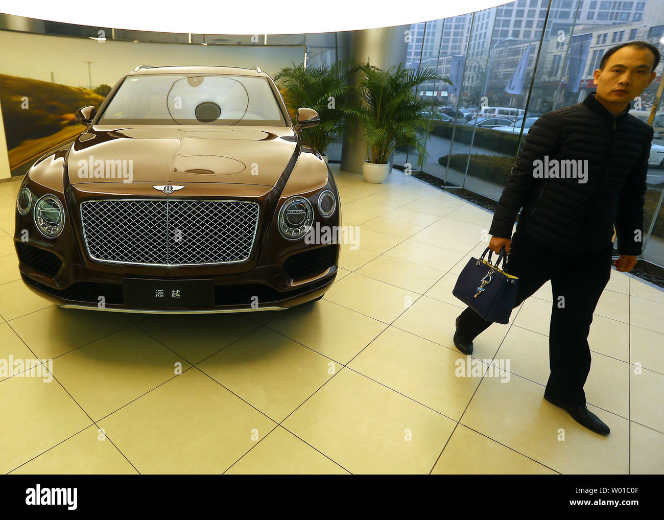 Un uomo cinese guarda al nuovo Bentley in uno showroom in centro a Pechino il 3 dicembre 2016. La Cina ha imposto un dieci per cento imposta su ultra high-end di lusso auto al costo di oltre $ 190.000 come Ferraris, Bentley, Aston Martins, Maserati, Lamborghini e Rolls-Rocye vetture di una repressione capillare sul consumo cospicuo e innesto, promuovendo al contempo la più efficiente del carburante dei veicoli. Foto di Stefano rasoio/UPI Foto Stock