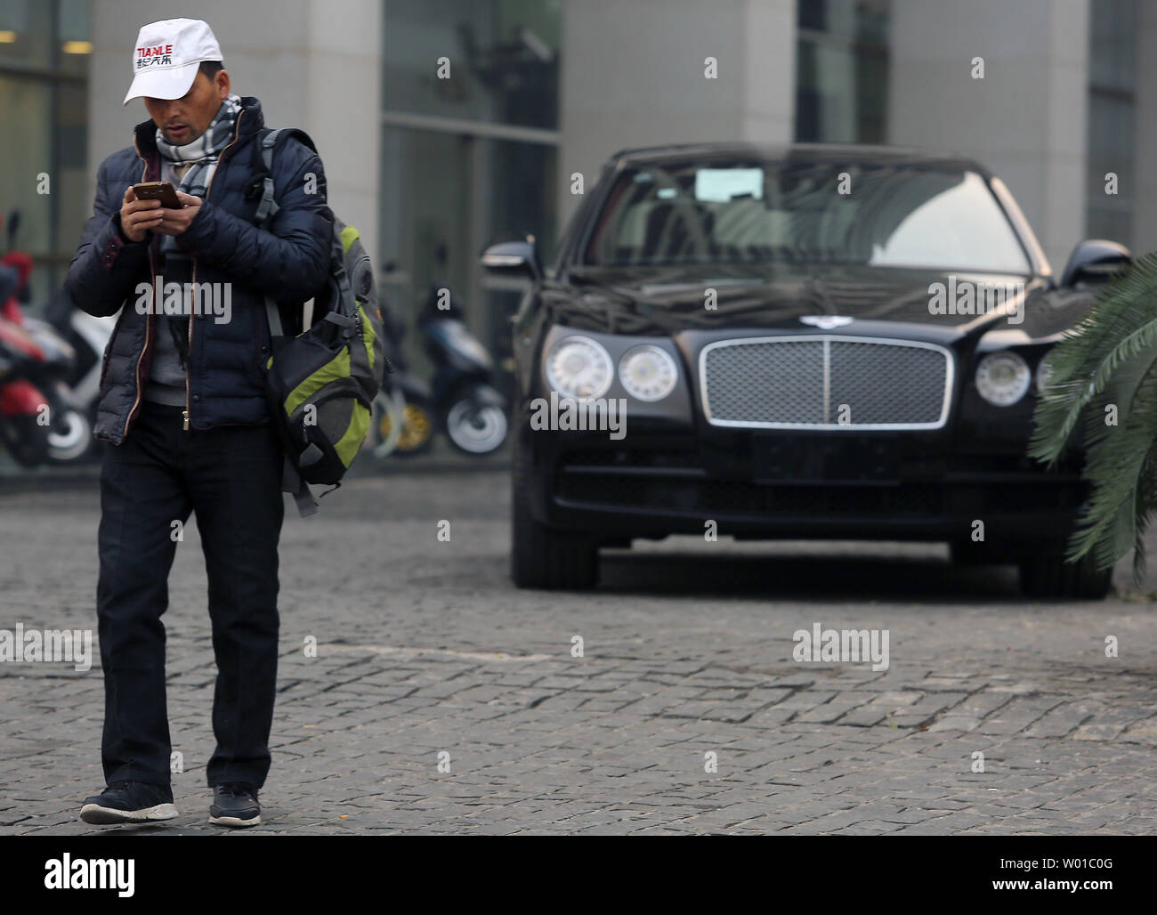 Un uomo cinese passeggiate passato una nuova Bentley al di fuori di uno showroom in centro a Pechino il 3 dicembre 2016. La Cina ha imposto un dieci per cento imposta su ultra high-end di lusso auto al costo di oltre $ 190.000 come Ferraris, Bentley, Aston Martins, Maserati, Lamborghini e Rolls-Rocye vetture di una repressione capillare sul consumo cospicuo e innesto, promuovendo al contempo la più efficiente del carburante dei veicoli. Foto di Stefano rasoio/UPI Foto Stock