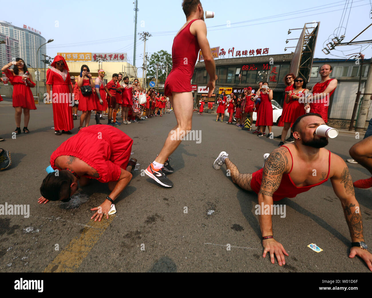 Entrambi i cinesi e stranieri uomini e donne indossare abiti di colore rosso mentre concorrenti nel bere birra gioco su una strada a Pechino durante l'Hash abito rosso carità eseguire il 17 giugno 2017. L'Hash House Harriers è un gruppo internazionale di non competitiva in funzione sociale club sponsor corse settimanali. Foto di Stefano rasoio/UPI Foto Stock