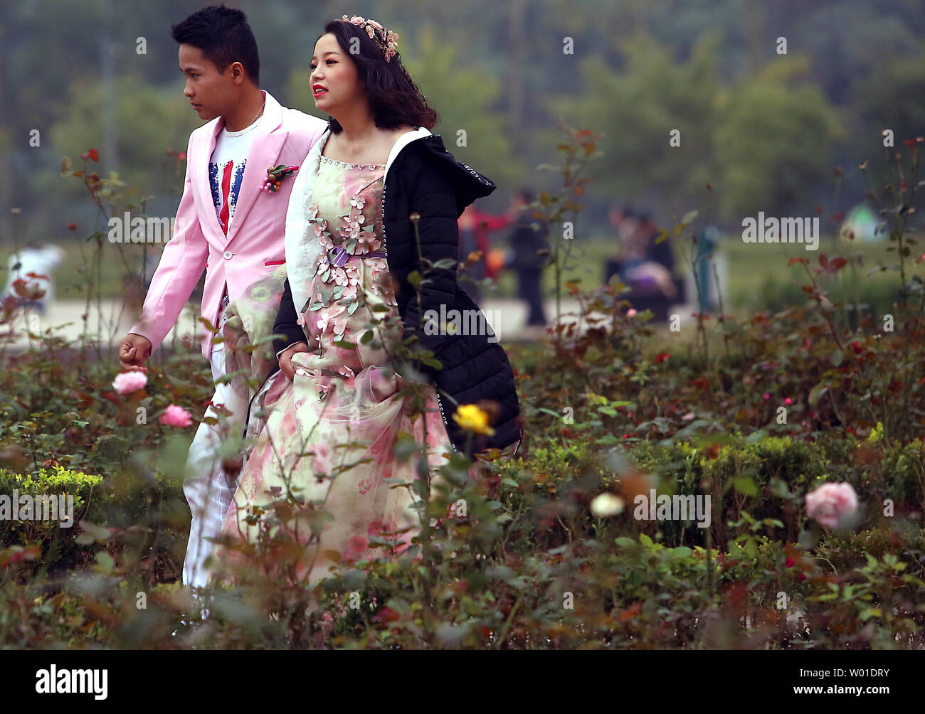 Un giovane cinese giovane passeggiate attraverso un parco sul loro modo ad un wedding photo shoot vicino a Pechino il 13 dicembre 2017. Atteggiamenti nei confronti della tradizionale matrimonio cinese sono state influenzate dai paesi occidentali, con più coppie oggi optare per il Western-style matrimoni. Foto di Stefano rasoio/UPI Foto Stock