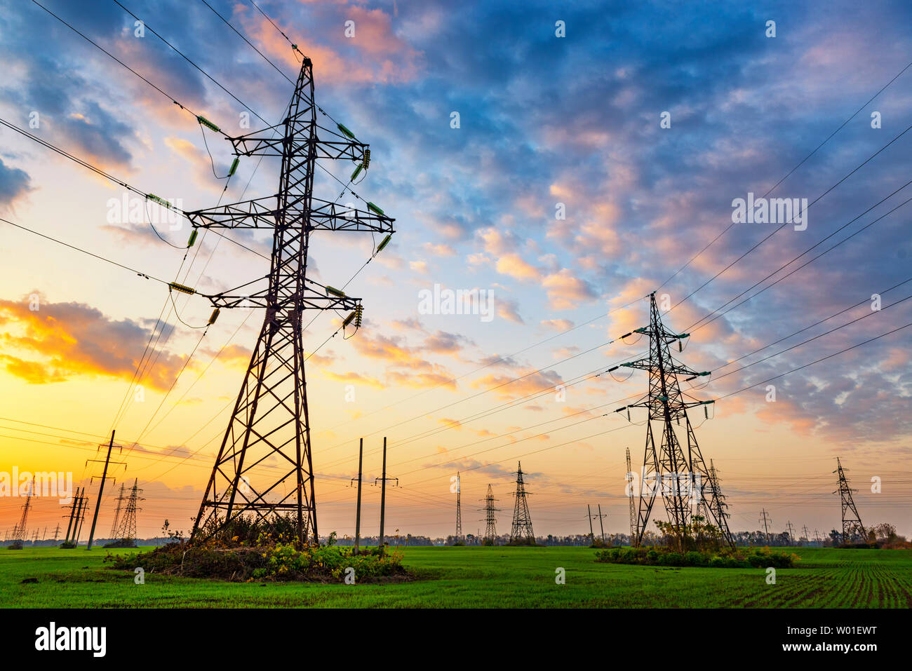 Le linee elettriche in alta tensione al tramonto. Vivid paesaggio industriale Foto Stock