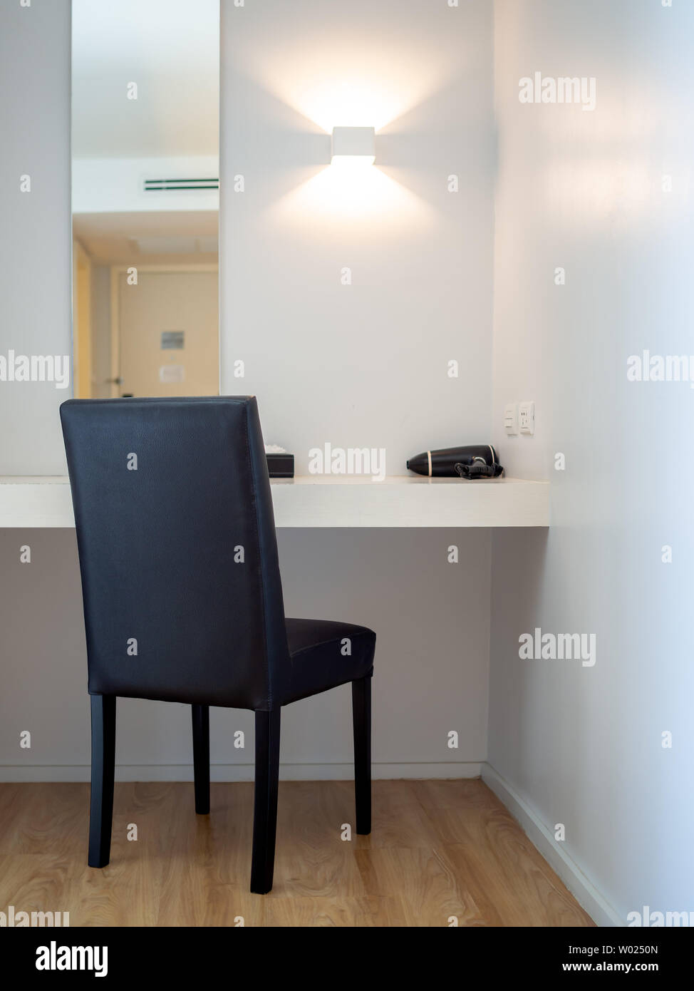 Angolo di trucco, sedia nero, nero asciugacapelli di fronte allo specchio e  lampada a parete in camera hotel stile verticale Foto stock - Alamy