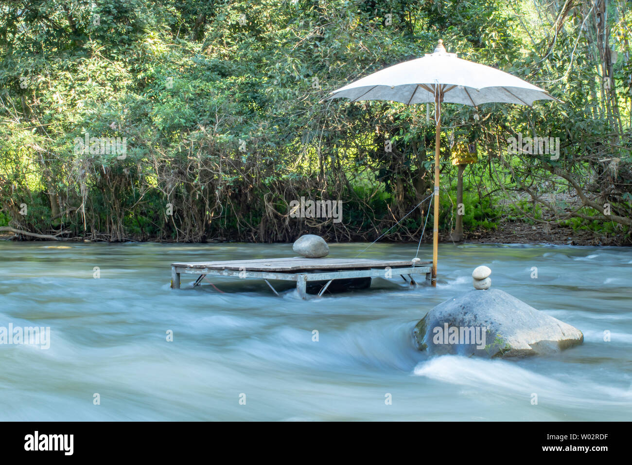 Tavolo in legno e ombrelloni nel flusso di Wang Nan Pua , Nan in Thailandia. Foto Stock
