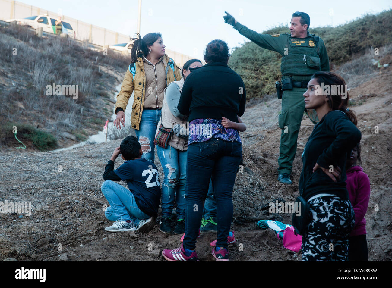 Una frontiera USA agente Patrol parla alle donne e ai bambini che attraversato illegalmente nel San Ysidro, California, il 2 dicembre 2018. Con la crescente frustrazione per la lunghezza della procedura di asilo, una dozzina di migranti decide di saltare la recinzione di confine che divide gli Stati Uniti e il Messico. Foto di Ariana Drehsler/UPI Foto Stock Una frontiera USA agente Patrol parla alle donne e ai bambini che attraversato illegalmente nel San Ysidro, California, il 2 dicembre 2018. Con la crescente frustrazione per la lunghezza della procedura di asilo, una dozzina di migranti decide di saltare la recinzione di confine che divide gli Stati Uniti e il Messico. Foto di Ariana Drehsler/UPI Foto Stock