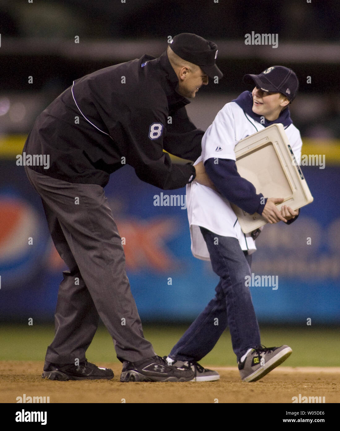 Primo sergente Steve Smeere, vestito con un uniforme arbitri sorprese il suo 13-anno-vecchio figlio, Kyle Smerer in seconda base durante il rubare-A-Base concorso organizzato nella quinta inning dei Seattle Mariners vs. Oakland Athletics game al Safeco Field di Seattle Aprile 13, 2013. Smerer, un soldato di stanza presso la base comune Lewis McChord, era in servizio in Afghanistan, ha contattato i marinai e ha chiesto se potevano aiutare in impostazione della sorpresa. UPI /Jim Bryant Foto Stock