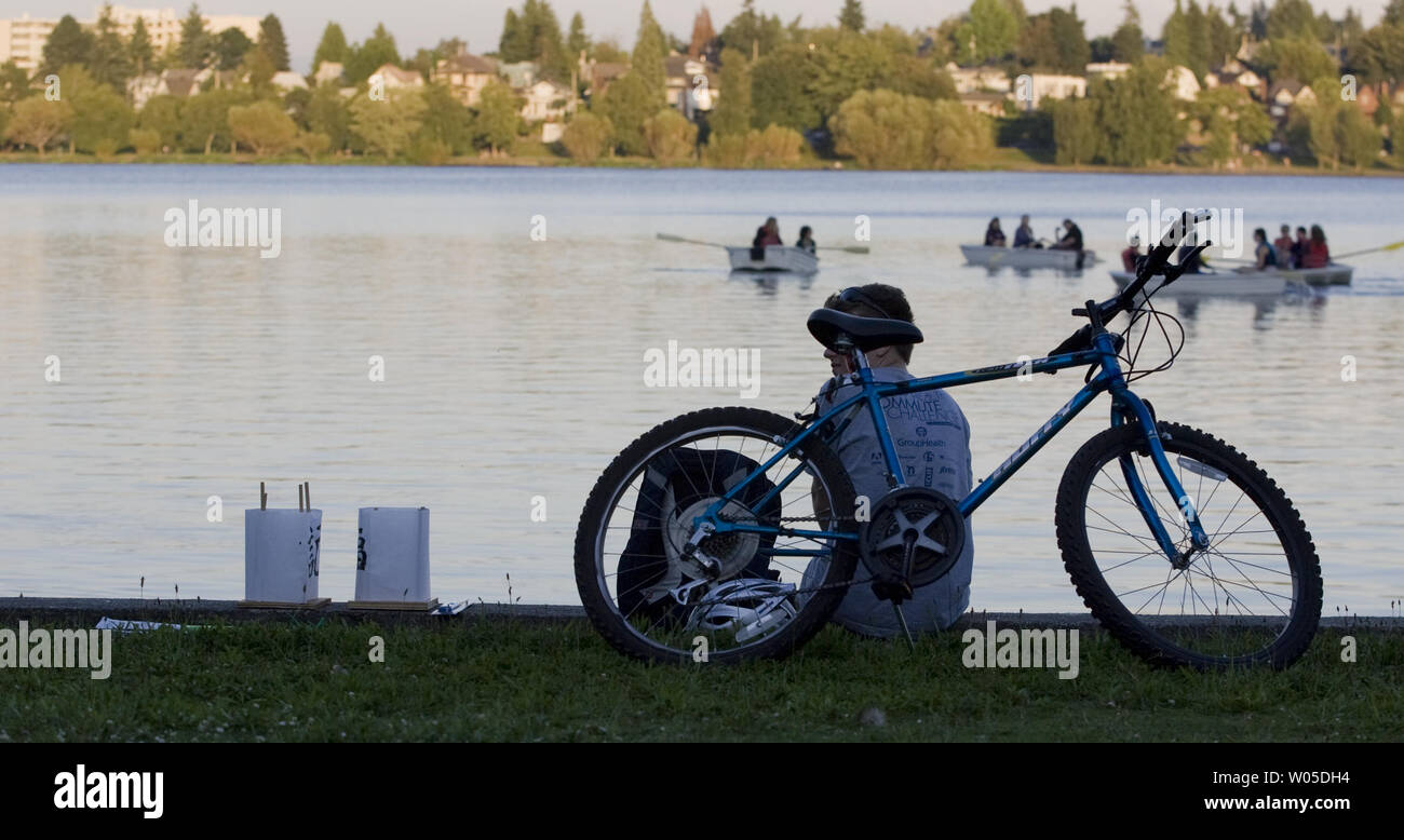 Stip Roberts si siede su una parete del lago in attesa di mettere le sue lanterne in verde lago durante la da Hiroshima per la speranza di una pace annuale manifestazione svoltasi a Seattle il 6 agosto 2012. Il Toro Nagshi LANTERNA OSCILLANTE cerimonia è un buddista giapponese rituale, in cui lanterne che rappresentano le anime dei morti sono negoziate in mare. La cerimonia viene rievocato ogni anno in questo momento a Hiroshima e Nagasaki e altre città in tutto il mondo in ricordo della bomba atomica vittime. (UPI foto/Jim Bryant)) Foto Stock