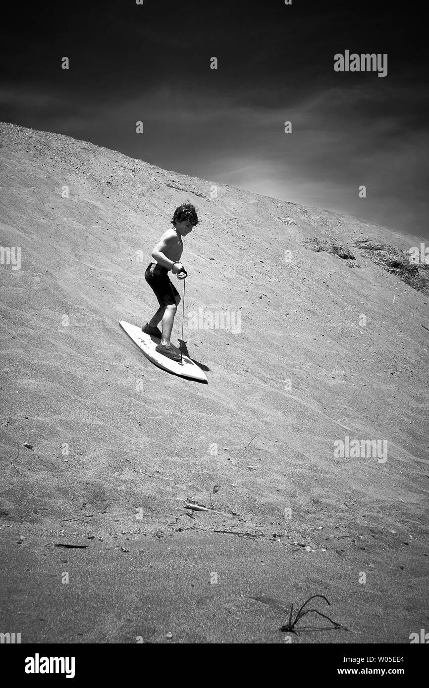 Un ragazzo sabbia surf su una duna di sabbia presso la costa del Pacifico e il fiume russo nei pressi di Jenner, California, in una giornata calda e soleggiata. Foto Stock