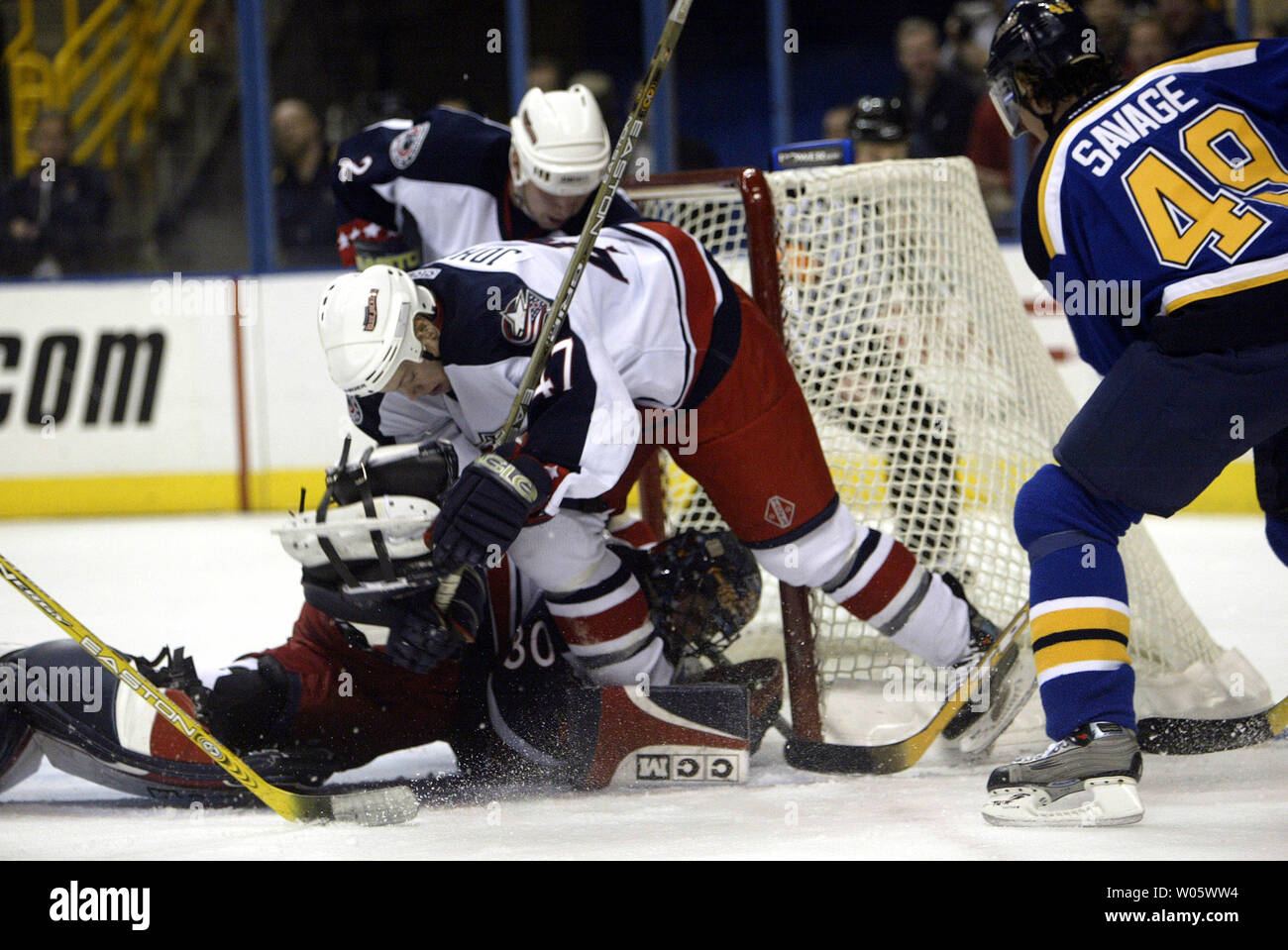 Columbus Giacche Blu goaltender Marc Denis giace su il puck off il bastone di San Louis Blues Brian Savage per il salvataggio come giacca blu di squadra Aaron Johnson (47) e Anders Eriksson tentare di aiutare nel secondo periodo al Savvis Center di San Louis il 13 marzo 2004. (UPI foto/Bill Greenblatt Foto Stock