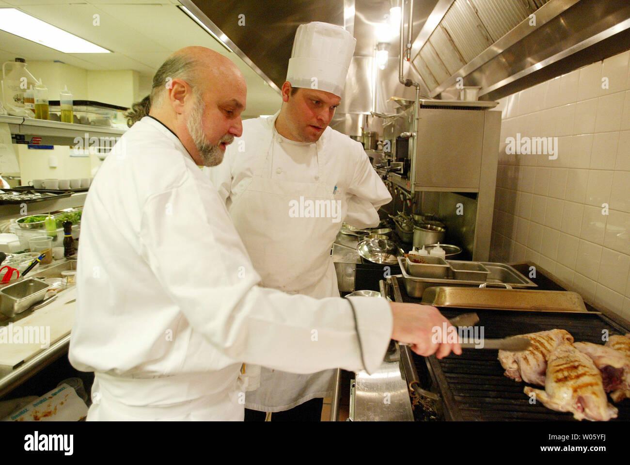 Il famoso chef e ristoratore Larry Forgione (L) mostra executive chef John  Griffiths il modo corretto per accendere un pollo alla griglia durante la  serata di apertura di Forgione è di nuovo
