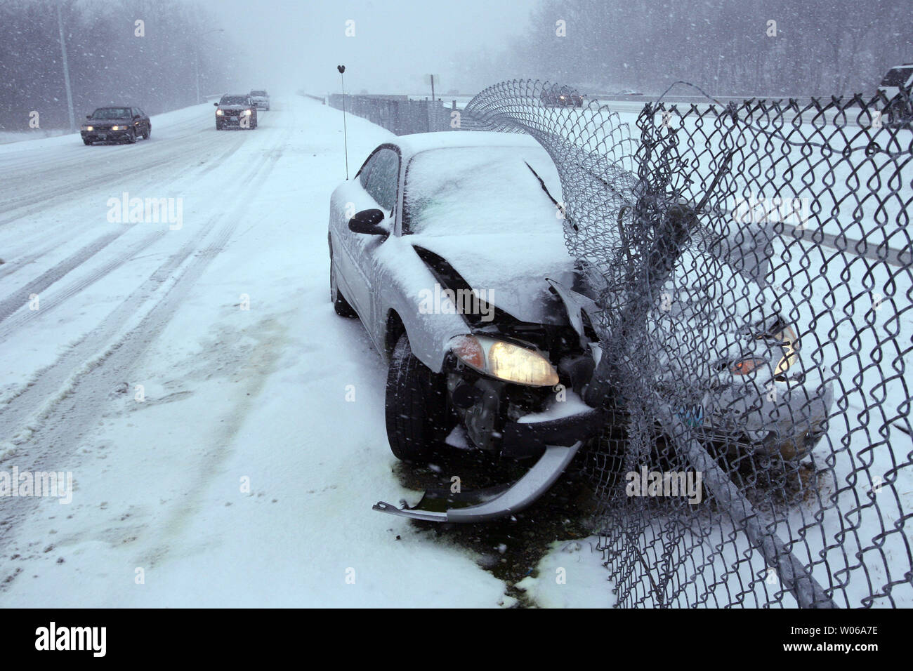 Gli automobilisti di viaggio passato lentamente un vacante vettura che si è schiantato in un recinto lungo l'autostrada 64 durante la fase di avviamento di un mattino nevicate in città e paese, Missouri il 13 febbraio 2007. Forecasters prevedono tra 4 a 6 cm di neve che cadrà a St Louis stasera. (UPI foto/Bill Greenblatt) Foto Stock