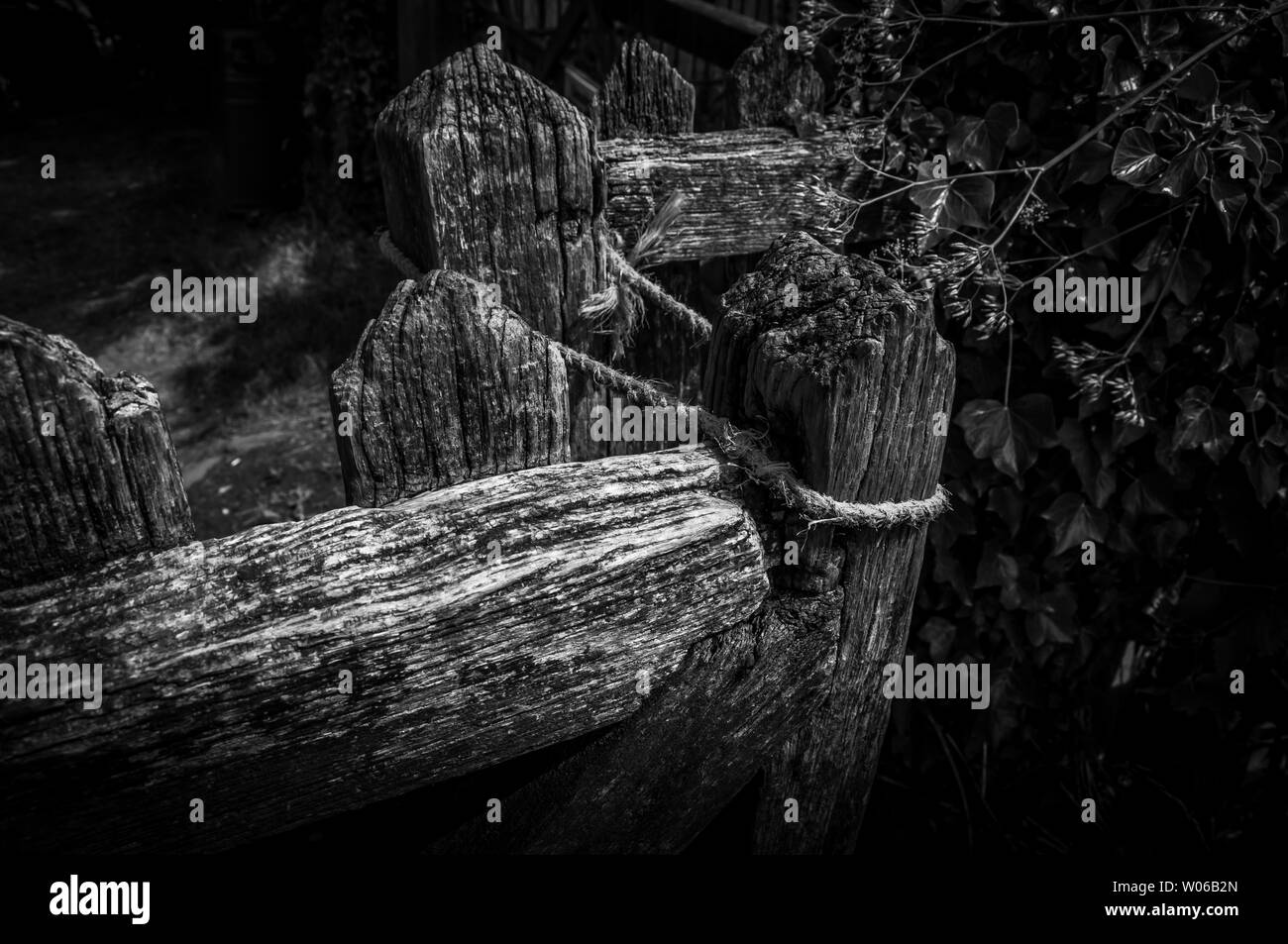 Una immagine in bianco e nero di una vecchia porta di legno mantenuto chiuso con la corda. Foto Stock