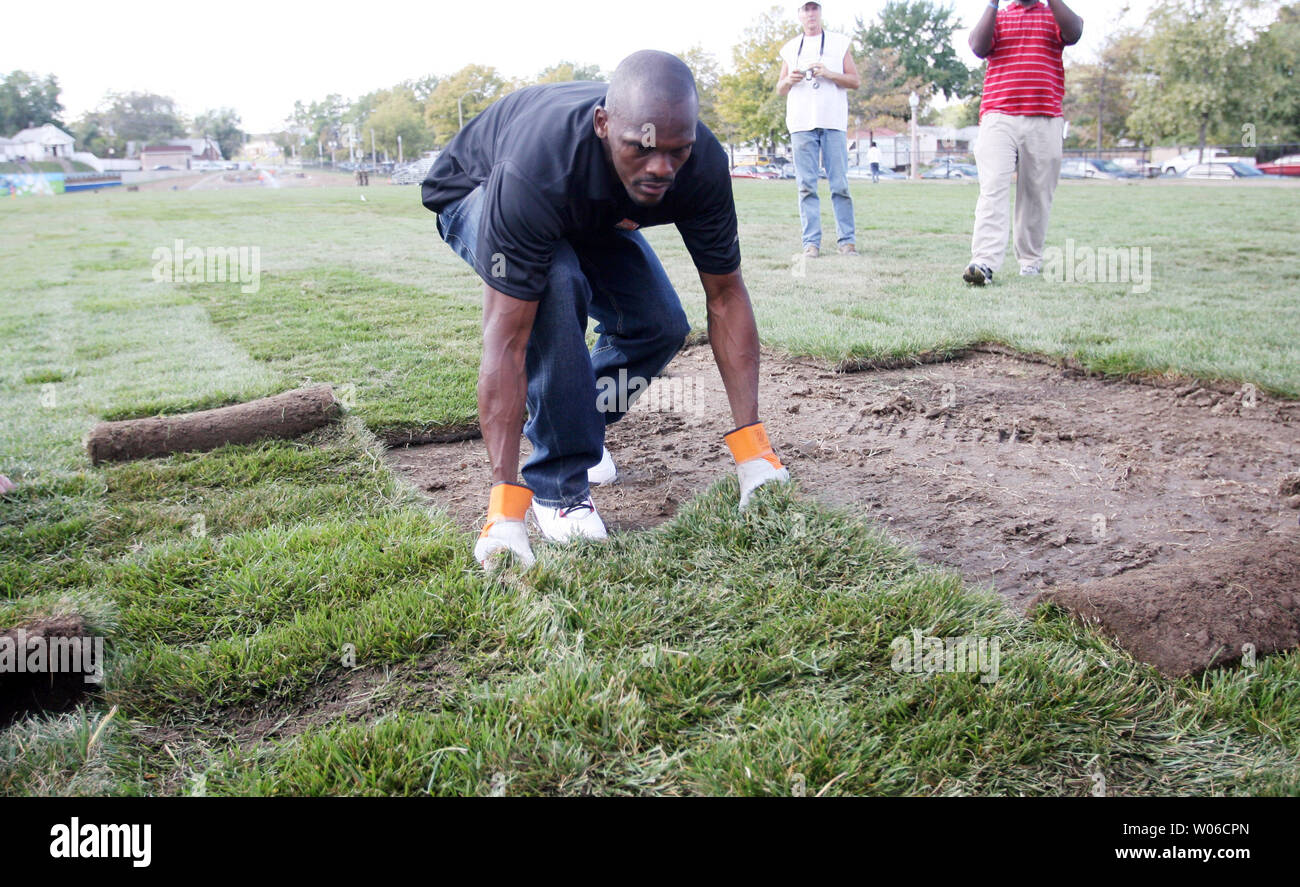 Louis Rams wide receiver Isaac Bruce rotola fuori un nuovo pezzo di sod come egli aiuta i volontari ri-sod il campo di calcio a nordovest di alta scuola nel nord di San Luigi il 16 ottobre 2007. I lavori di ristrutturazione è parte di uno sforzo nazionale nazionale dal quartiere programma MVP per creare e fissare 1.000 campi in 1.000 giorni. (UPI foto/Bill Greenblatt) Foto Stock