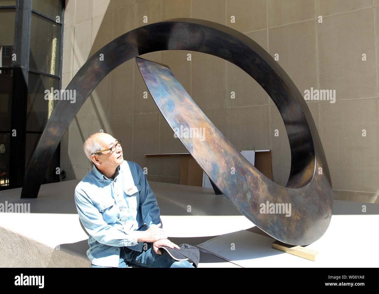 Seattle artista Gerard Tsutakawa guarda oltre la sua scultura "Uzumaki curva' dopo i lavoratori collocati nella sua nuova casa in Clayton, Missouri il 3 maggio 2011. Il 1000 lb scultura in bronzo rappresenta un tema di naturalmente le curve a spirale ed è il suo primo pezzo nel midwest. UPI/Bill Greenblatt Foto Stock