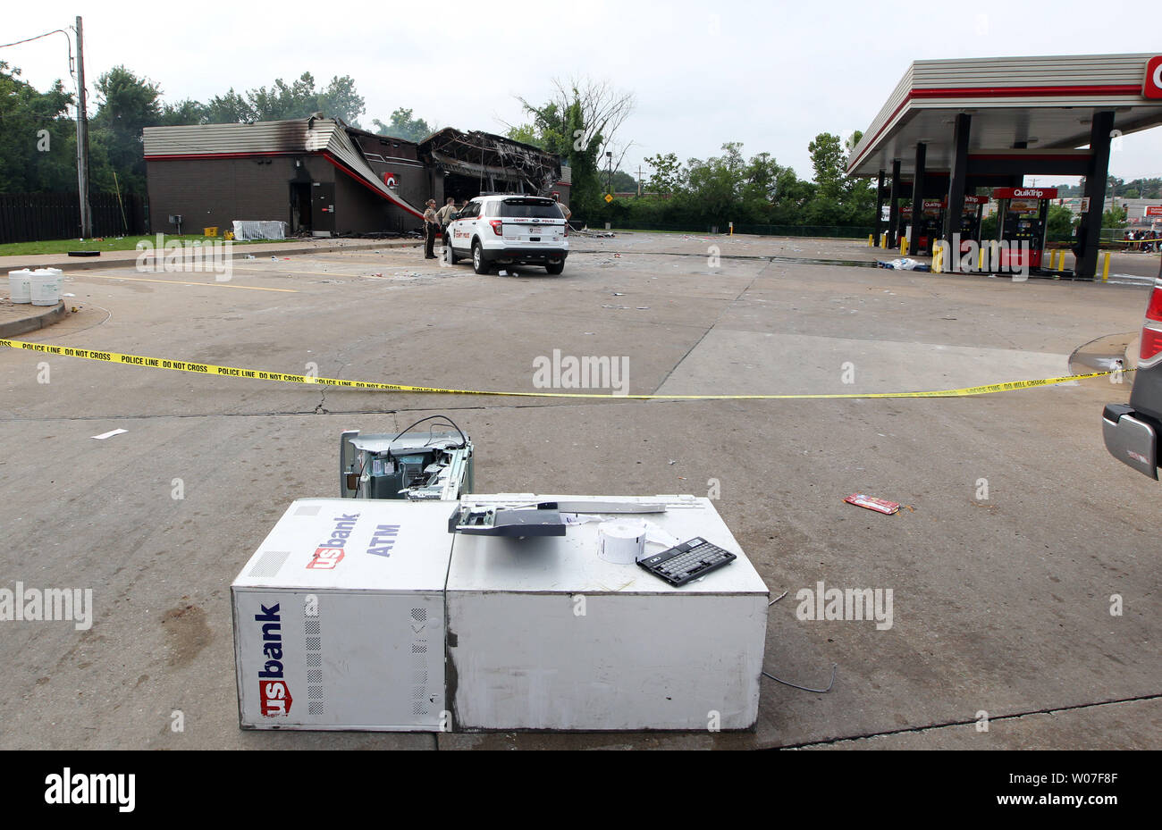 San Luigi di polizia della contea di posizionarsi su un Gas QuickTrip staton che è stata bruciata, mentre una macchina ATM stabilisce nel parcheggio dopo una notte di saccheggio, disordini e incendi in Ferguson, Missouri il 11 agosto 2014. Le persone sono sconvolto perché della Ferguson riprese di polizia e la morte di un inerme adolescente nero Michael Brown il 9 agosto 2014. In tutto circa 20 aziende subito danni dopo una veglia a lume di candela è diventata violenta. UPI/Bill Greenblatt Foto Stock