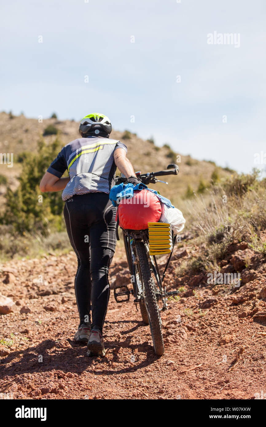 L'uomo ciclista spingendo il suo turismo in bicicletta sulle colline lungo il G10 a lunga distanza trail in Montes Universales montagne di orientale della Spagna Foto Stock