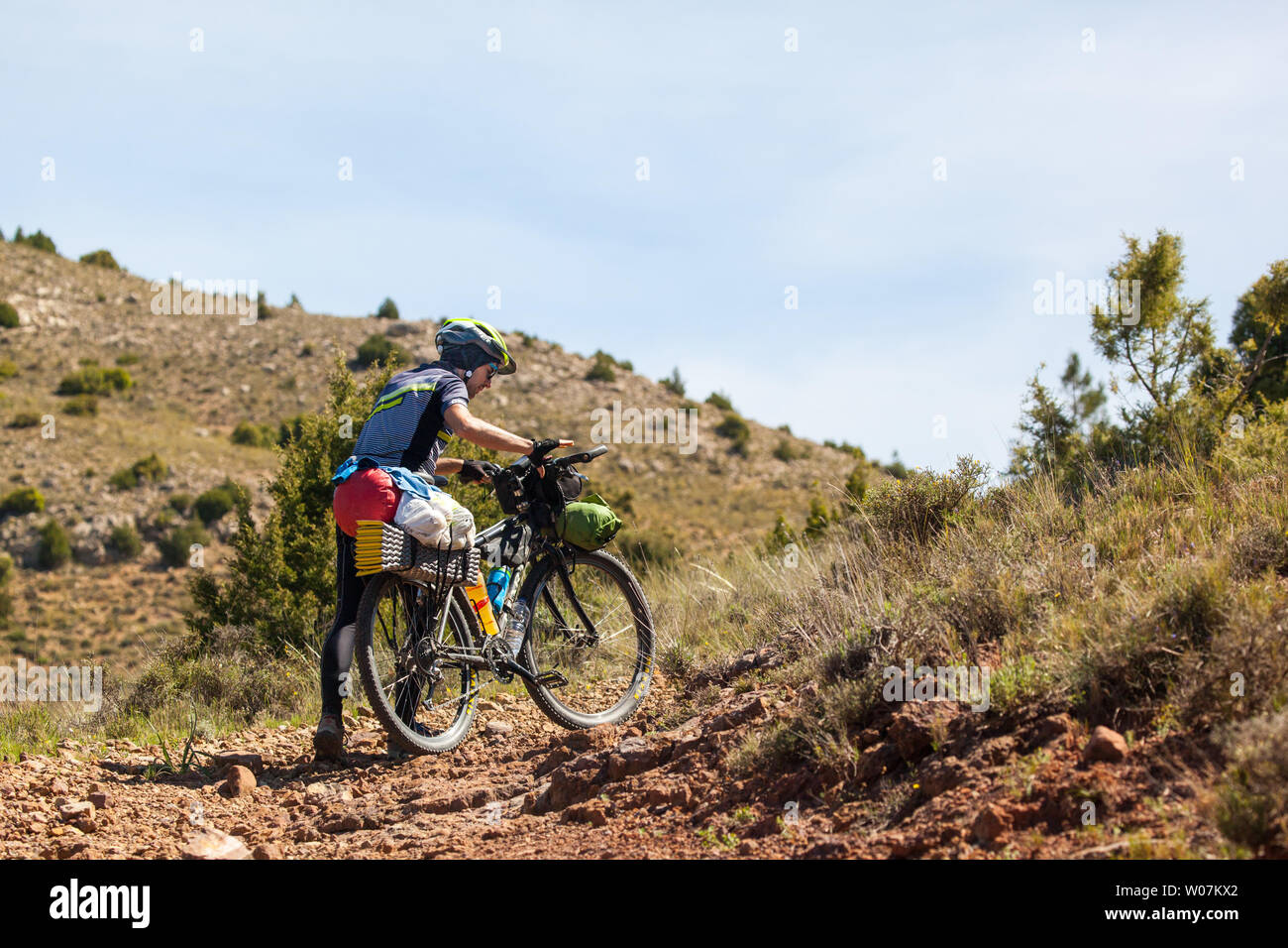 L'uomo ciclista spingendo il suo turismo in bicicletta sulle colline lungo il G10 a lunga distanza trail in Montes Universales montagne di orientale della Spagna Foto Stock