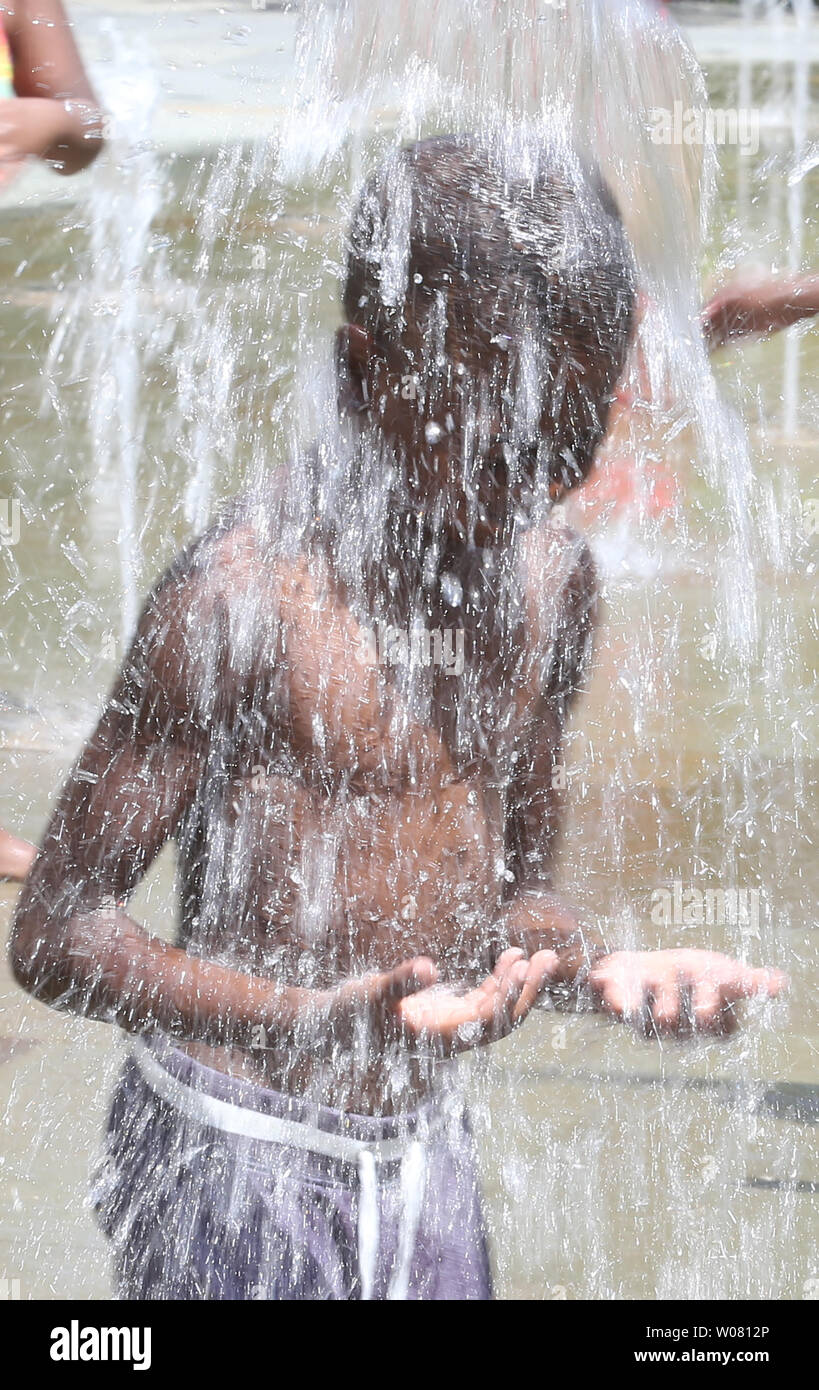 Un giovane bambino trova rilievo sotto i getti di acqua nel giardino della città come un gruppo di bambini prova a battere il 103-grado di temperatura a San Louis sulla luglio 12, 2017. Forecasters predire triple-digit temperature a durare per almeno un giorno in più. Foto di Bill Greenblatt/UPI Foto Stock