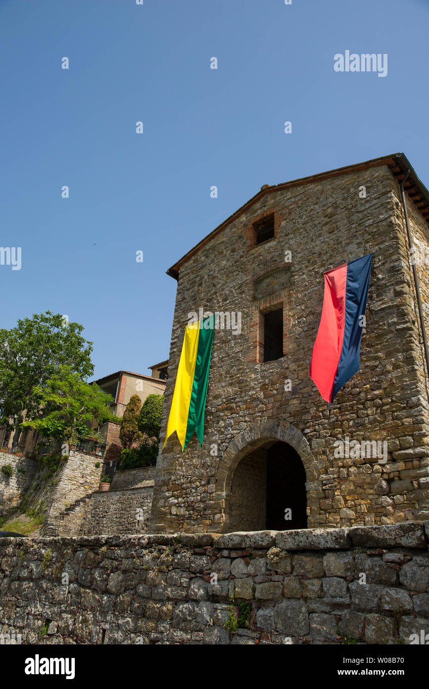 Muro medievale porta d'ingresso del borgo fortificato di Lucignano, Toscana, Italia, con banner colorati. Colpo verticale. Foto Stock