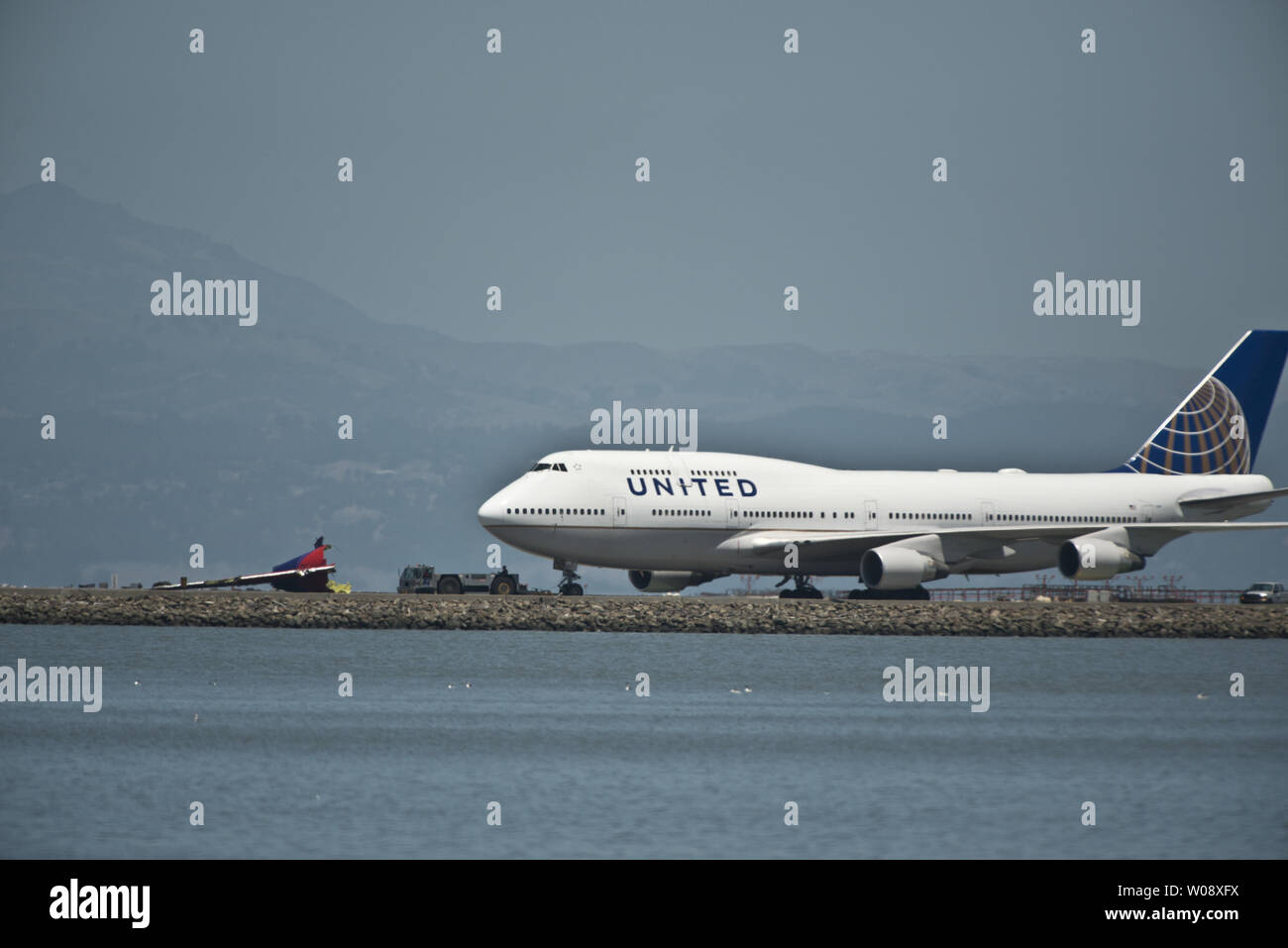 Un piano di unita è trainato dalla sezione di coda di un'Asiana Air Boeing 777 dopo l'Asiana piallato si è schiantato in atterraggio sulla pista di San Francisco Aeroporto Internazionale di San Francisco il 6 luglio 2013. Il piano è stato proveniente da Seoul. UPI/Terry Schmitt Foto Stock
