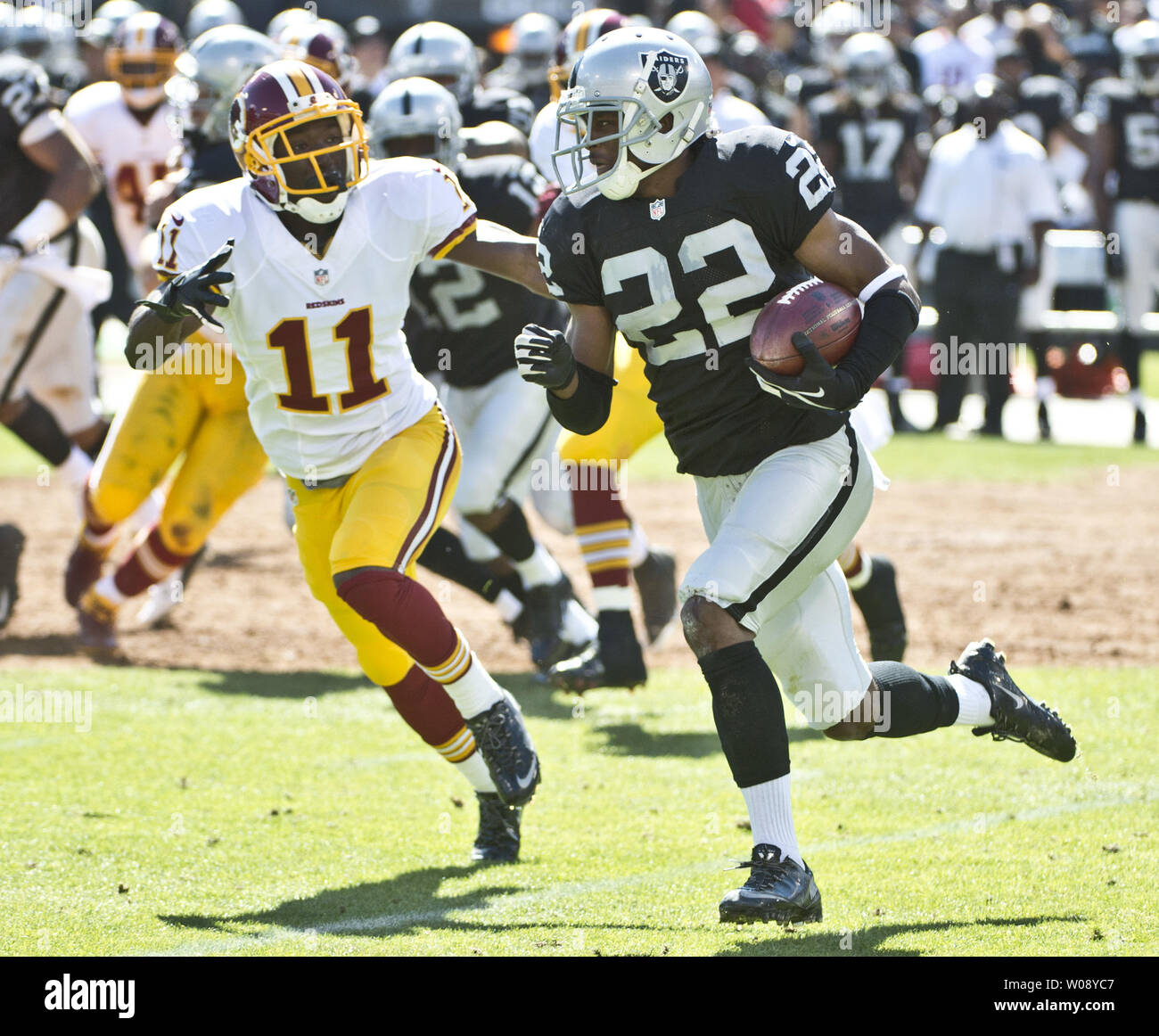 Oakland Raiders Taiwan Jones (22) corre 19 yards su uno scatto diretto da un punt formazione perseguita da Washington Redskins Aldrick Robinson (11) nel secondo trimestre a O.co Coliseum di Oakland, la California il 29 settembre 2013. Le pellerosse sconfitto i raider 24-14. UPI/Terry Schmitt Foto Stock