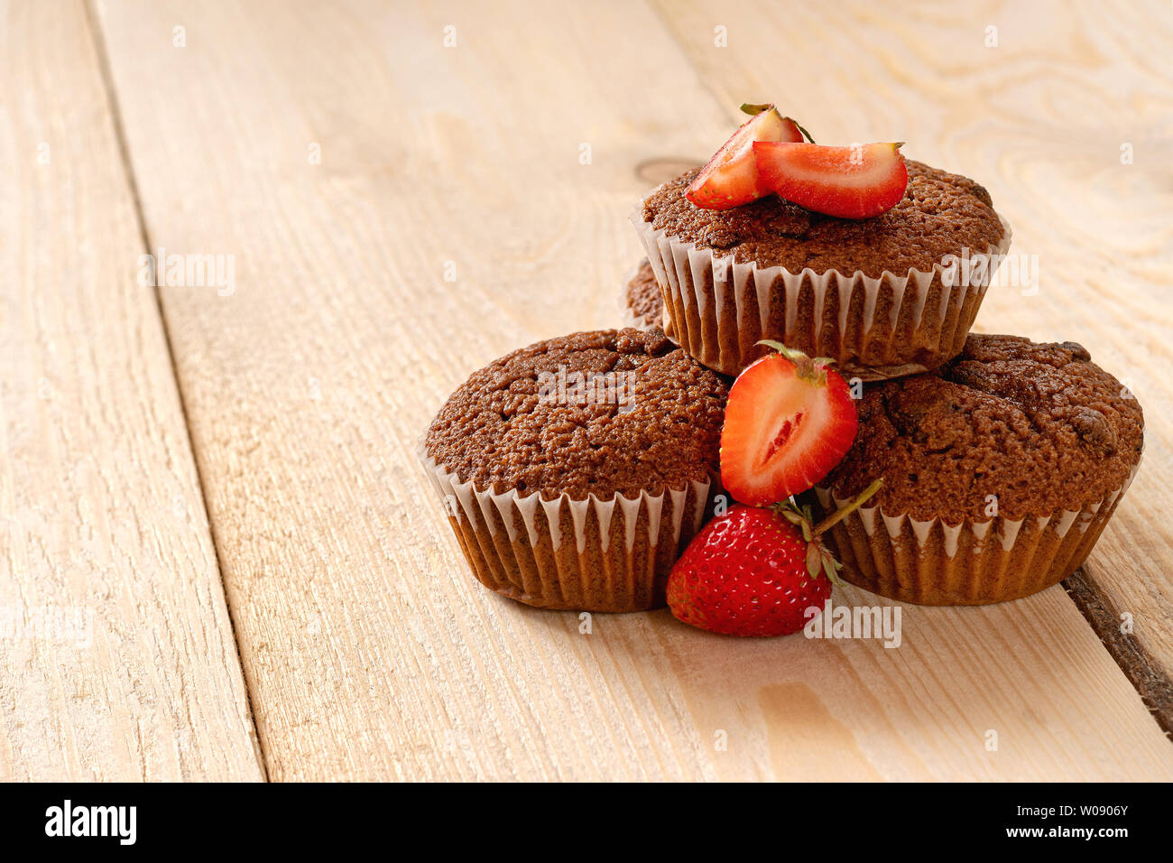 Piramide di muffin con fragole fresche luce sul tavolo di legno. Foto Stock