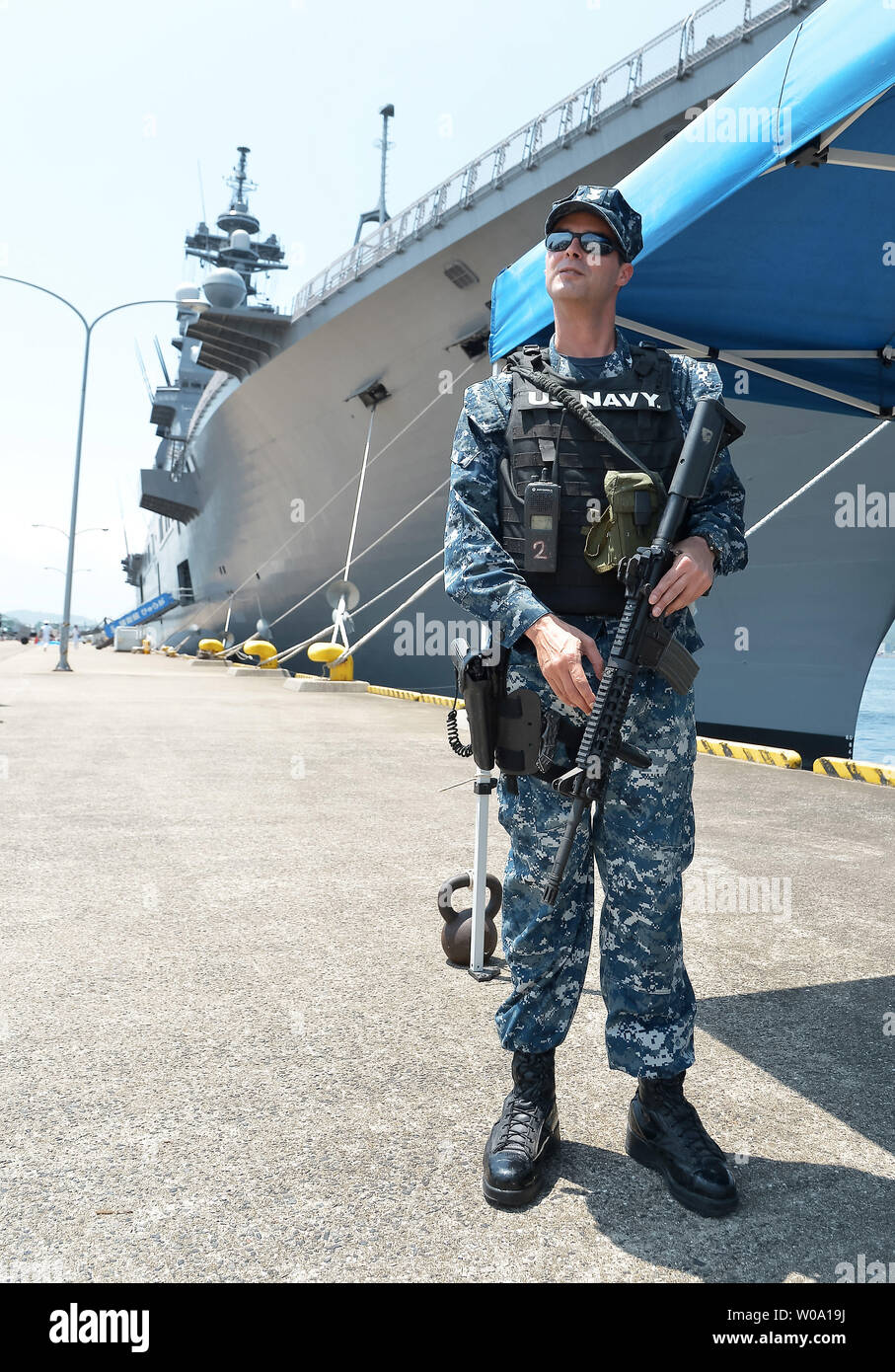 Marinaio di U.S. Navy stand protezione nella parte anteriore del Giappone marittimo Forza di Autodifesa's elicottero destroyer JS Hyuga (DDH181) a U.S. Le attività della flotta Sasebo, Prefettura di Nagasaki, Giappone il 10 giugno 2016. Foto di Keizo Mori/UPI Foto Stock