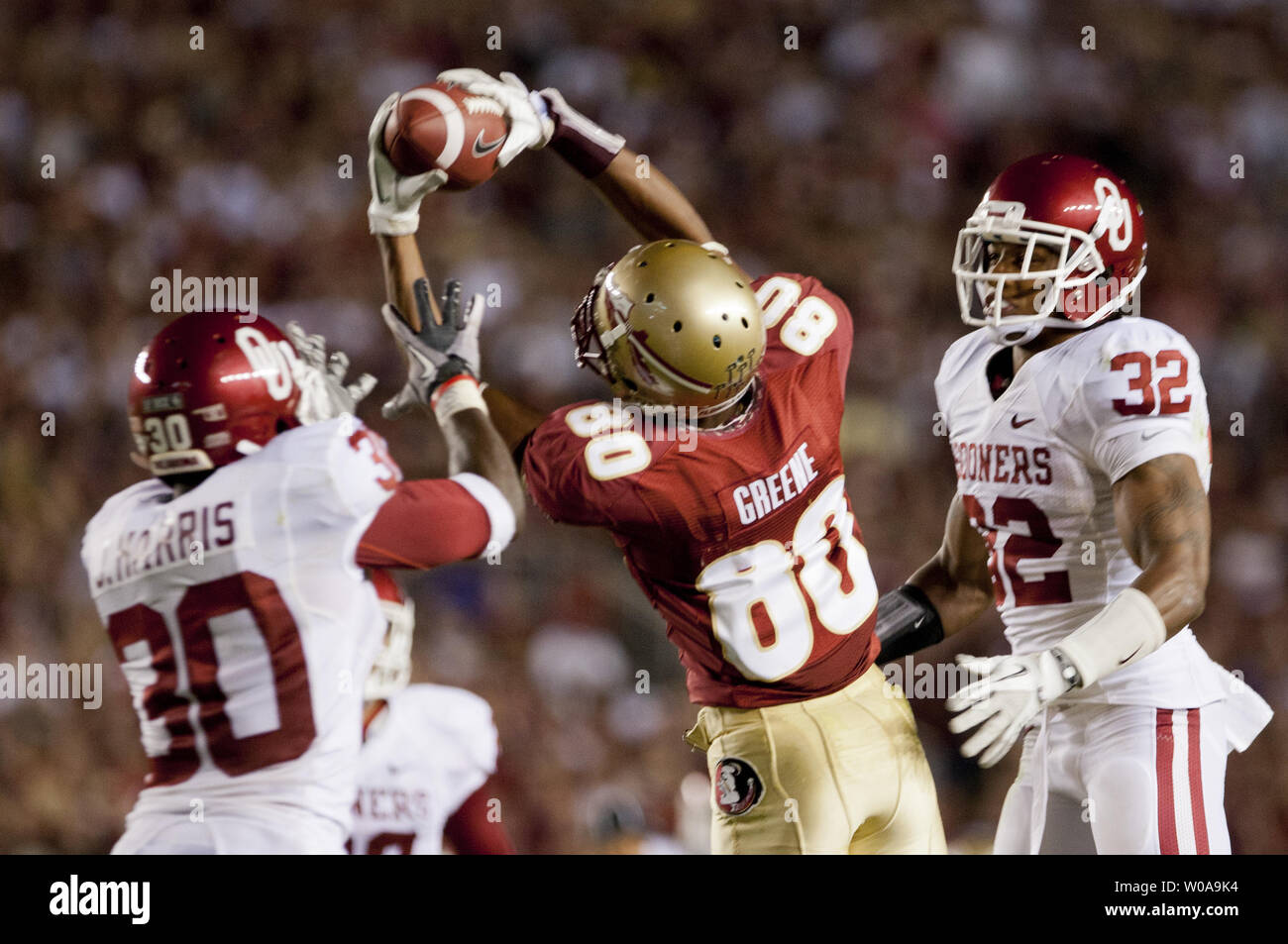 Stato della Florida ricevitore Rashad Greene (80) fa una dichiarazione delle catture tra Oklahoma difensori Javon Harris (30) e Jamell Fleming (32) e stampati 56 cantieri per un touchdown nella seconda metà del loro NCAA Football gioco in Tallahassee, Florida 17 Sett 2011. L'Oklahoma Sooners sconfitto Stato della Florida Sminoles 23-13. UPI/Mark Wallheiser Foto Stock