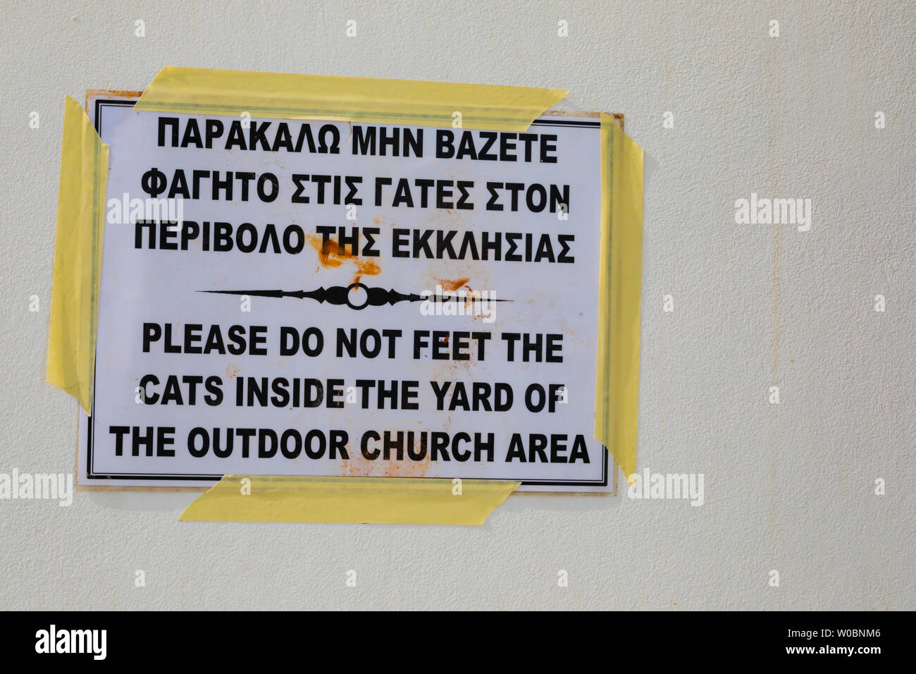 Segno attenzione a non alimentare i gatti, con errore di ortografia. La cappella di Agia Triada, città di Paralimni, Cipro. giugno 2019 Foto Stock