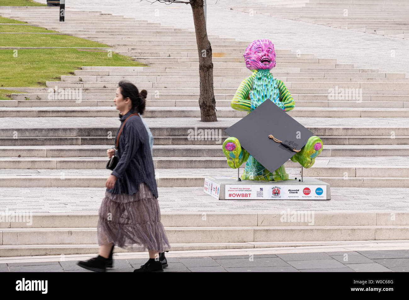 Glasgow, Scotland, Regno Unito - 22 Giugno 2019: due giovani donne a camminare lungo la moderna statua del "nostro Wullie' anteriore della nuova città di Glasgow College Foto Stock