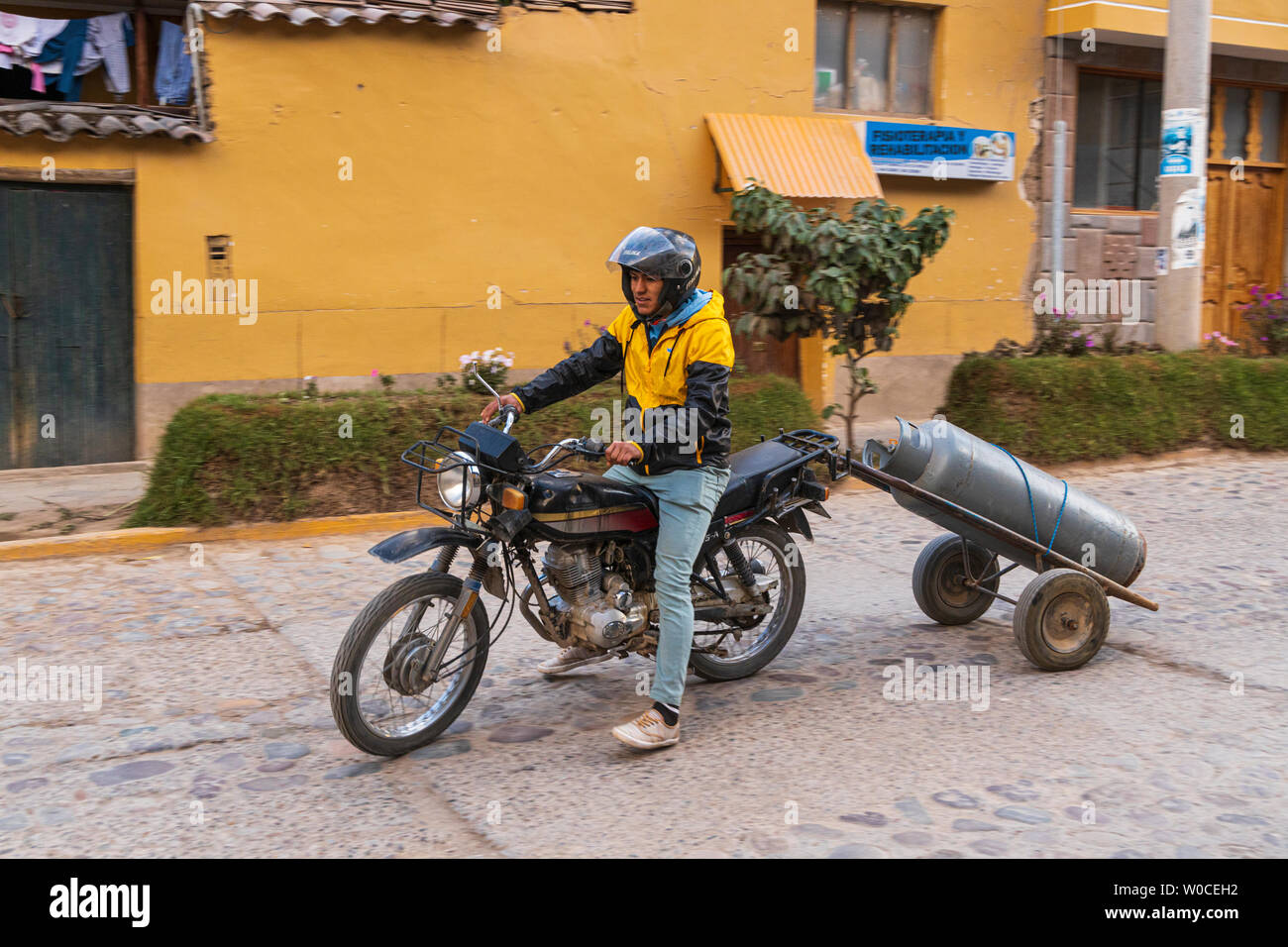 L'uomo sul motociclo carrello di traino con il gas propano bottiglia, Ollantaytambo, Valle Sacra, Perù, Sud America Foto Stock