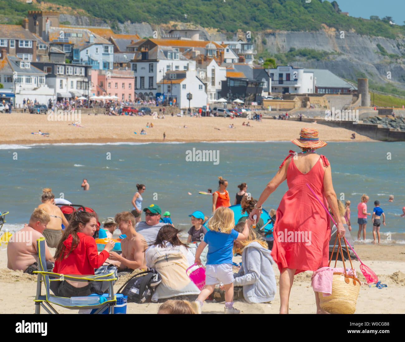 Lyme Regis, Dorset, Regno Unito. Il 27 giugno 2019. Regno Unito: Meteo Sunseekers gregge alla pittoresca località balneare di Lyme Regis per godersi il caldo torrido sole e cieli azzurri come la canicola sahariana colpisce il Regno Unito. I visitatori locali e crogiolarvi al sole soffocante sul comune di sabbia della spiaggia. Credito: Celia McMahon/Alamy Live News. Foto Stock