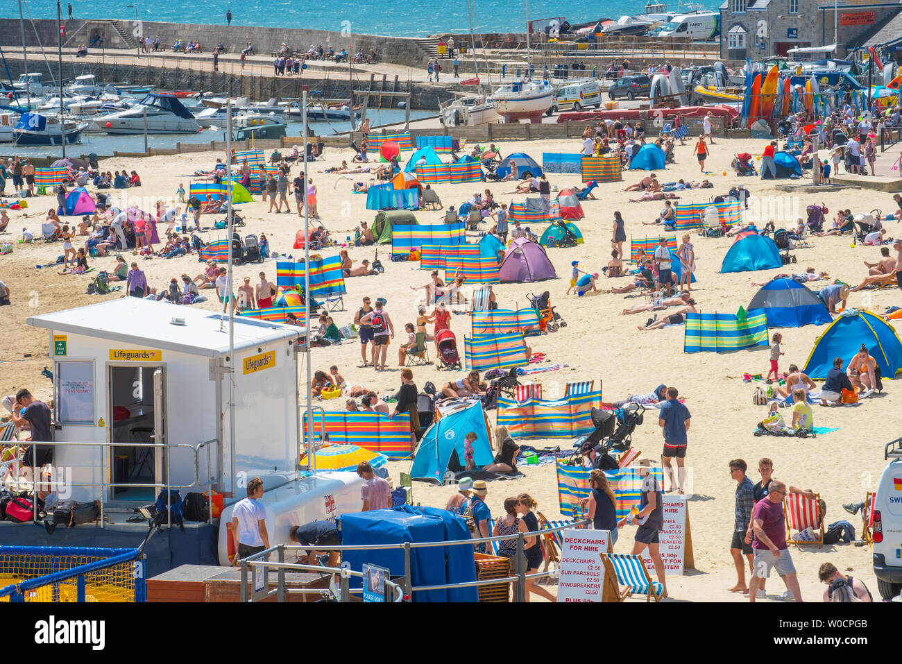 Lyme Regis, Dorset, Regno Unito. Il 27 giugno 2019. Regno Unito: Meteo Sunseekers gregge alla pittoresca località balneare di Lyme Regis per godersi il caldo torrido sole e cieli azzurri come la canicola sahariana colpisce il Regno Unito. I visitatori locali e crogiolarvi al sole soffocante sul comune di sabbia della spiaggia. Credito: Celia McMahon/Alamy Live News. Foto Stock