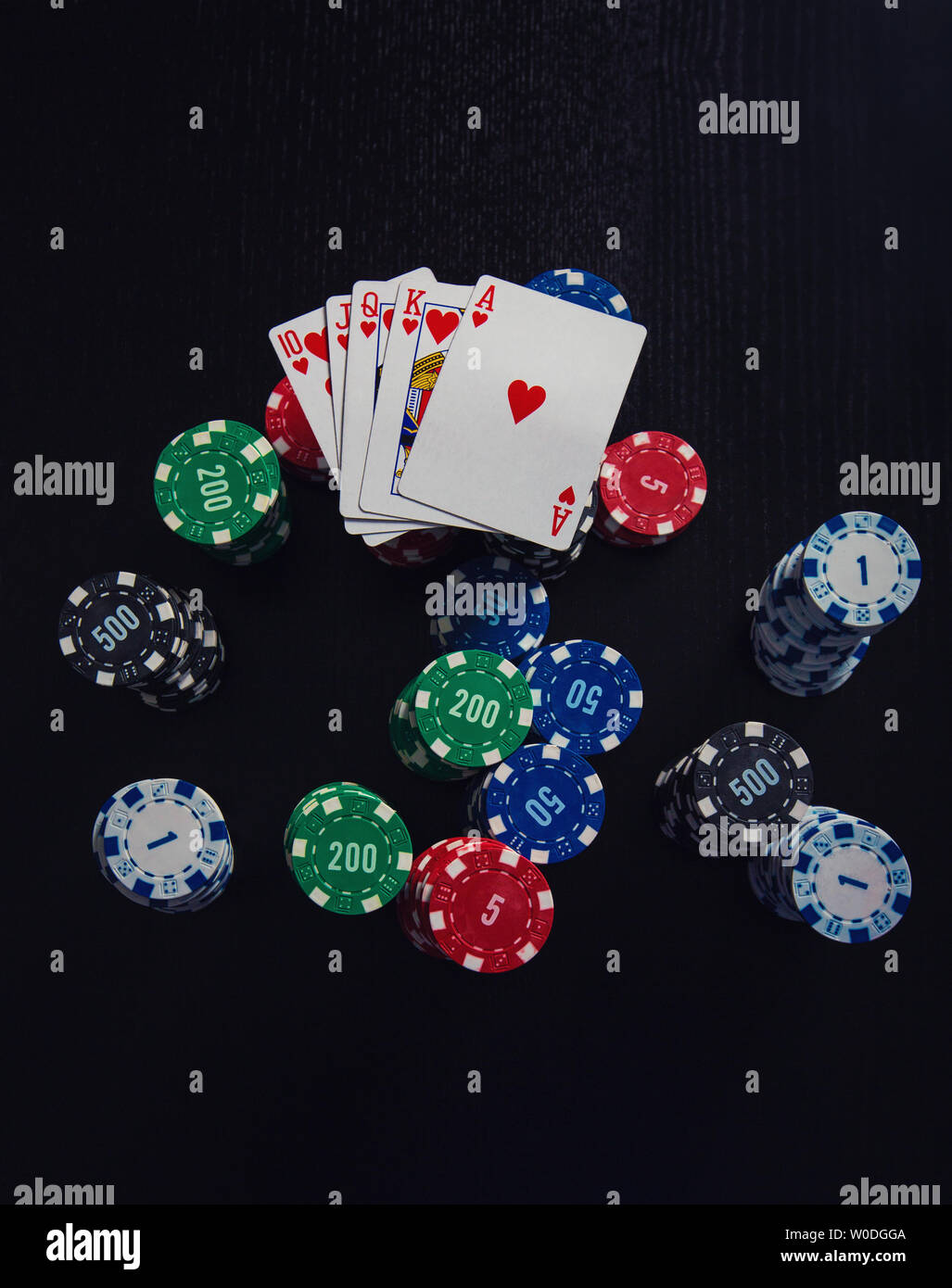 Grande pila di chip diversi e la combinazione più alta di carte da gioco poker - royal flush isolate su casino nero tabella. Il gioco d'azzardo tourname Foto Stock