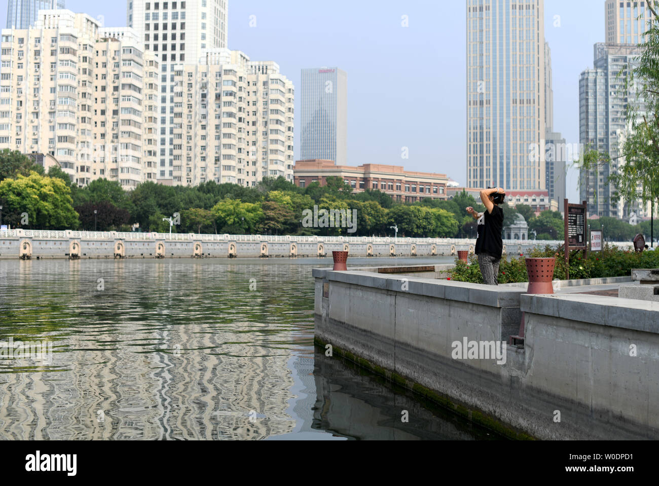 (190627) -- TIANJIN, 27 giugno 2019 (Xinhua) -- una donna asporta dal Fiume Haihe nel nord della Cina di Tianjin, 27 giugno 2019. Haihe, conosciuta come la città "fiume altro', corre per oltre 70 km dal Comune di Tianjin a Dagukou dove esso si svuota nel mare Bohai. Oggi quasi 30 ponti span attraverso Haihe e molti grattacieli in stand by il fiume. Haihe è diventata una delle principali della cinghia del paesaggio di Tianjin, con la sua acqua limpida e bellissima vista lungo la banca. (Xinhua/Yue Yuewei) Foto Stock