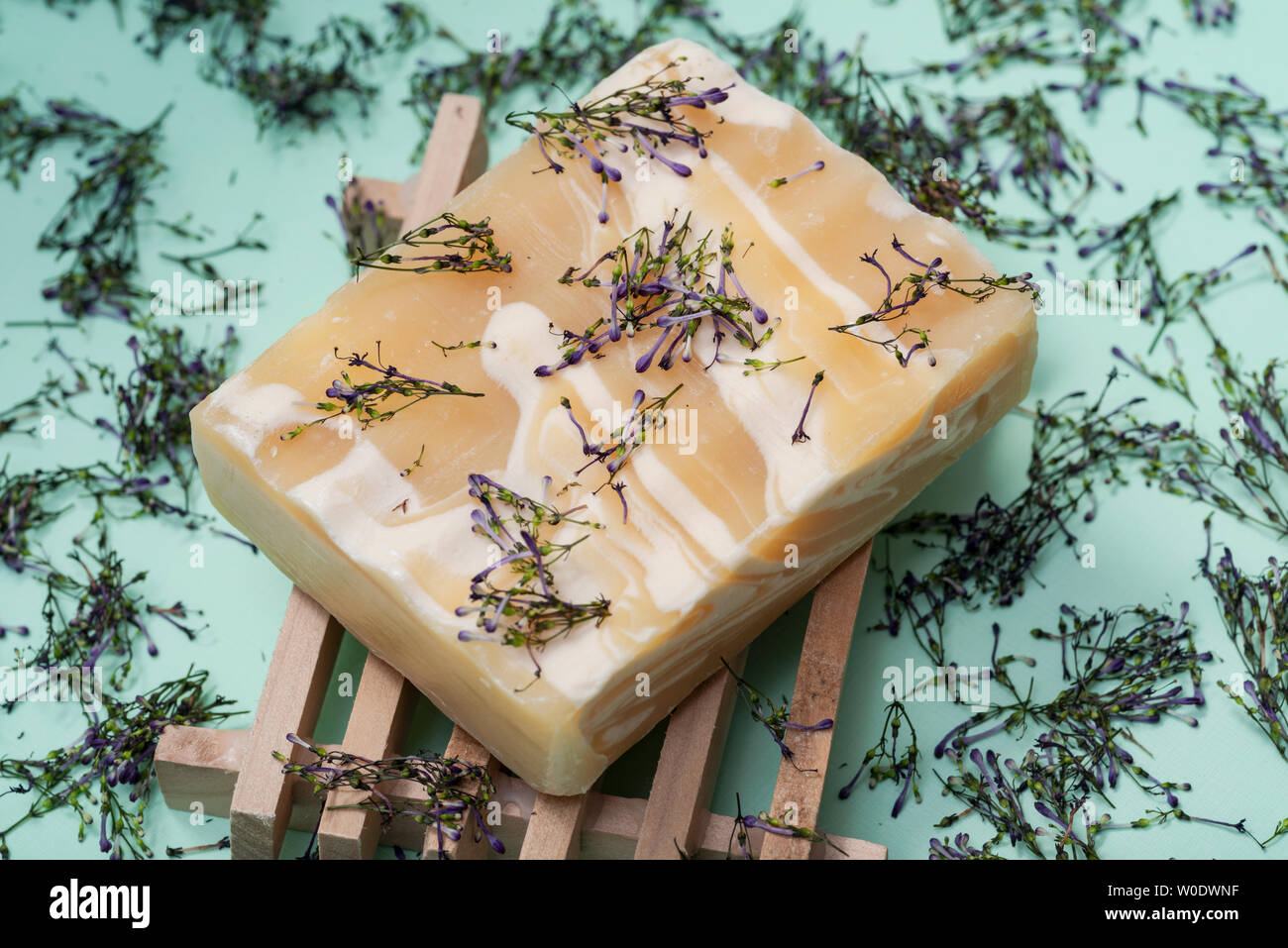 In legno porta sapone fatto a mano di ultra-idratante profumata di mandorle Latte di capra sapone bar decorato con fiore spruzza coriandoli su sfondo verde. Foto Stock