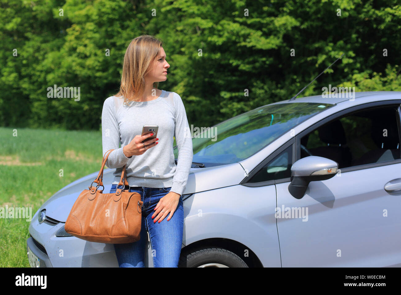 Giovane donna in attesa su auto Foto Stock