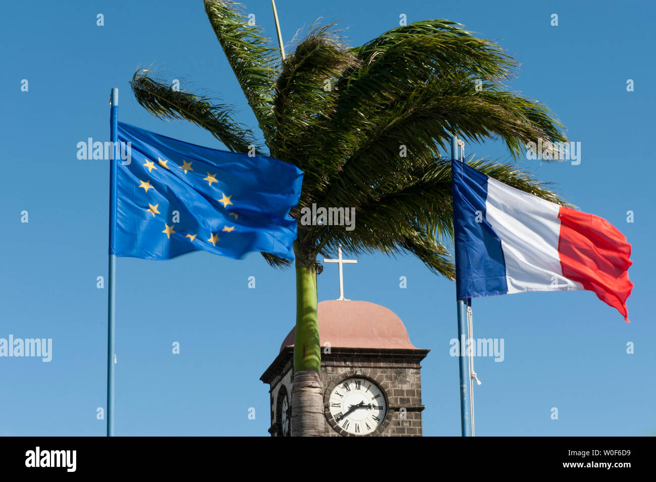 Campanile della chiesa sotto il palm tree e bandiere, San Giuseppe, La Réunion, territori di oltremare, Francia Foto Stock