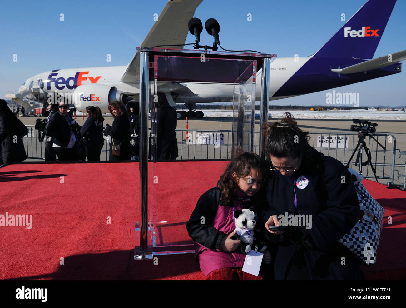 Distretto di Columbia Segretario Stephanie Scott (R) e sua figlia di 8 anni Mattie Melnyk attendere per la partenza di Tai Shan, un bambino di 4 anni maschio panda gigante, vicino a FedEx Express 777 cargo aereo all'Aeroporto di Dulles a Dulles, Virginia il 4 febbraio 2010. Tai Shan e un altro di 3 anni panda femmina, Mei Lan, dallo Zoo di Atlanta, sarà trasportato sulla "FedEx Panda Express' a Chengdu, in Cina per entrare a far parte del paese allevamento e programma di conservazione. Entrambi i panda sono di proprietà del governo cinese e sono state affittate a gli Stati Uniti. UPI/Alexis C. Glenn. Foto Stock
