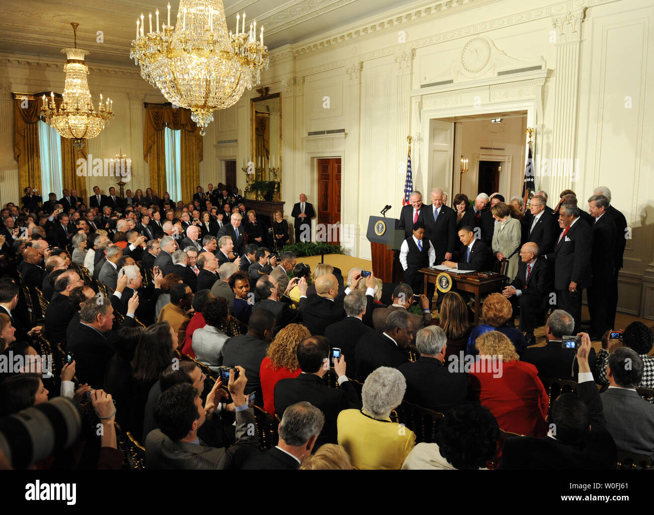 Stati Uniti Il presidente Barack Obama firma l'assicurazione sanitaria riforma di legge circondato da gli ospiti invitati e membri del Congresso nella Sala Est della Casa Bianca di Washington il 23 marzo 2010. Il centro storico di $938 milioni di health care bill sarà garantita la copertura per 32 milioni di americani non assicurati e toccherà quasi ogni americano la vita. UPI/Pat Benic Foto Stock