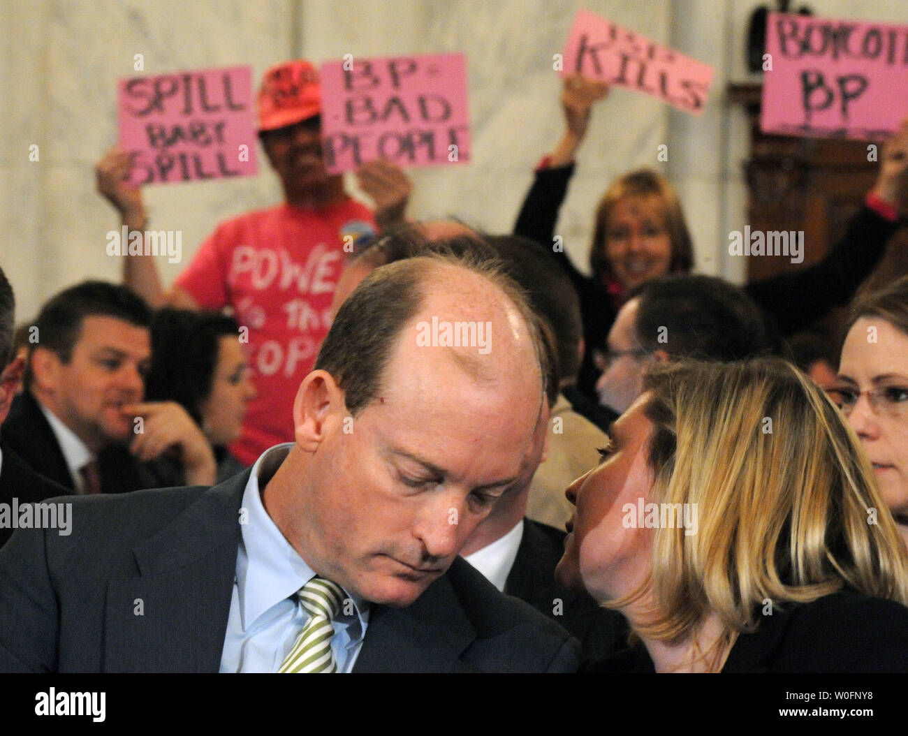 Lamar McKay (L), Presidente e Presidente di BP America Inc., parla di un aiuto come egli attende a testimoniare come i manifestanti tenere cartelli contro la BP durante un senato di energia e di risorse naturali audizione del Comitato BP Deepwater Horizon oil rig incidente nel Golfo del Messico, a Washington il 11 maggio 2010. UPI/Kevin Dietsch Foto Stock