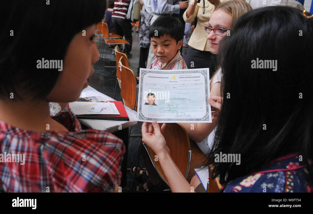 La famiglia di Linden Yong Kang Reeder (C), nato in Cina, tiene il suo certificato di cittadinanza dopo che lui e 24 bambini in rappresentanza di 18 paesi hanno preso il giuramento di fedeltà a una cerimonia di naturalizzazione presso lo Smithsonian, il Museo Nazionale di Storia Americana a Washington il 12 giugno 2010. UPI/Alexis C. Glenn Foto Stock